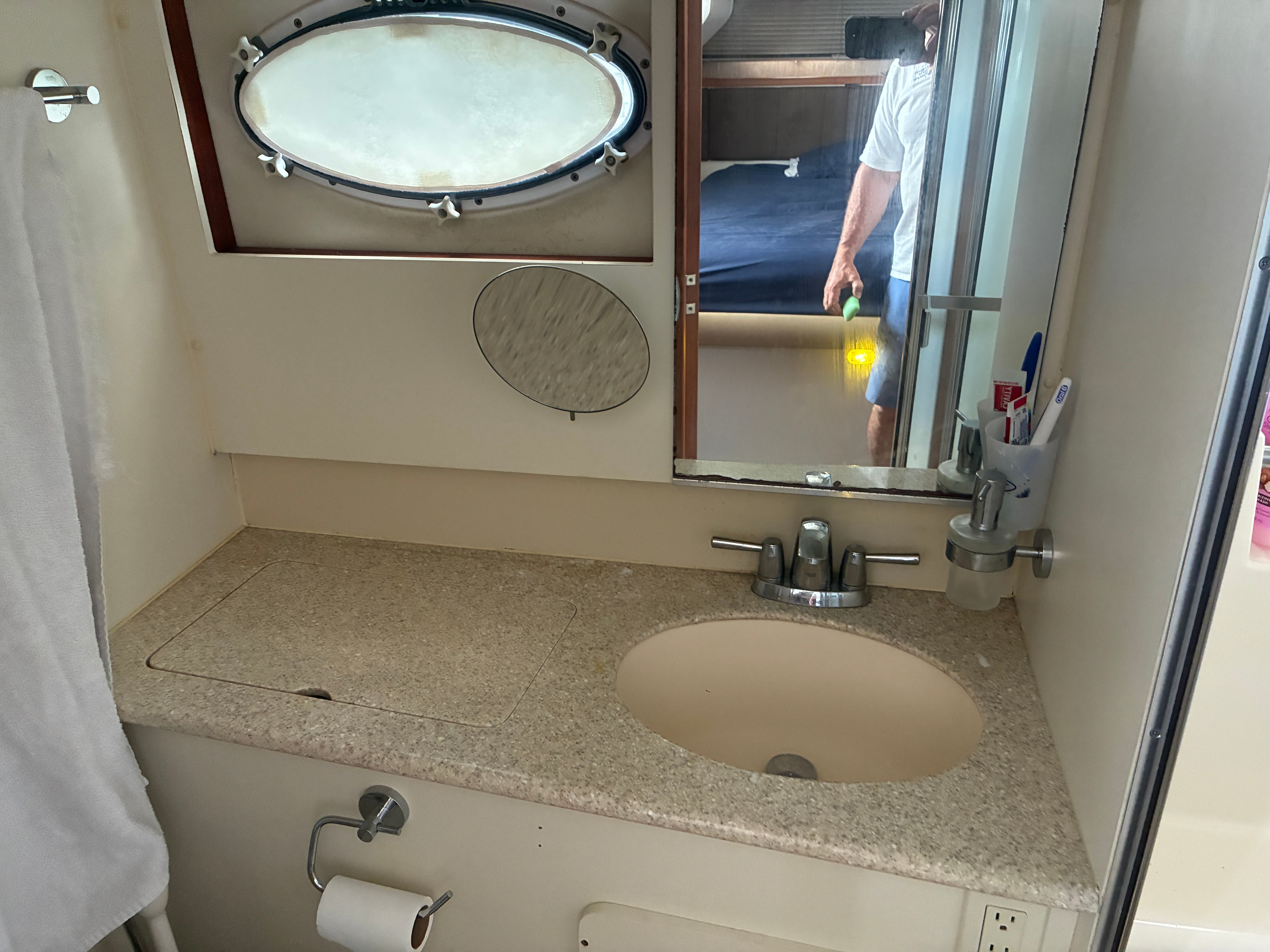 Bathroom with sink, mirror, and porthole in a 2001 Silverton 392 Motor Yacht.