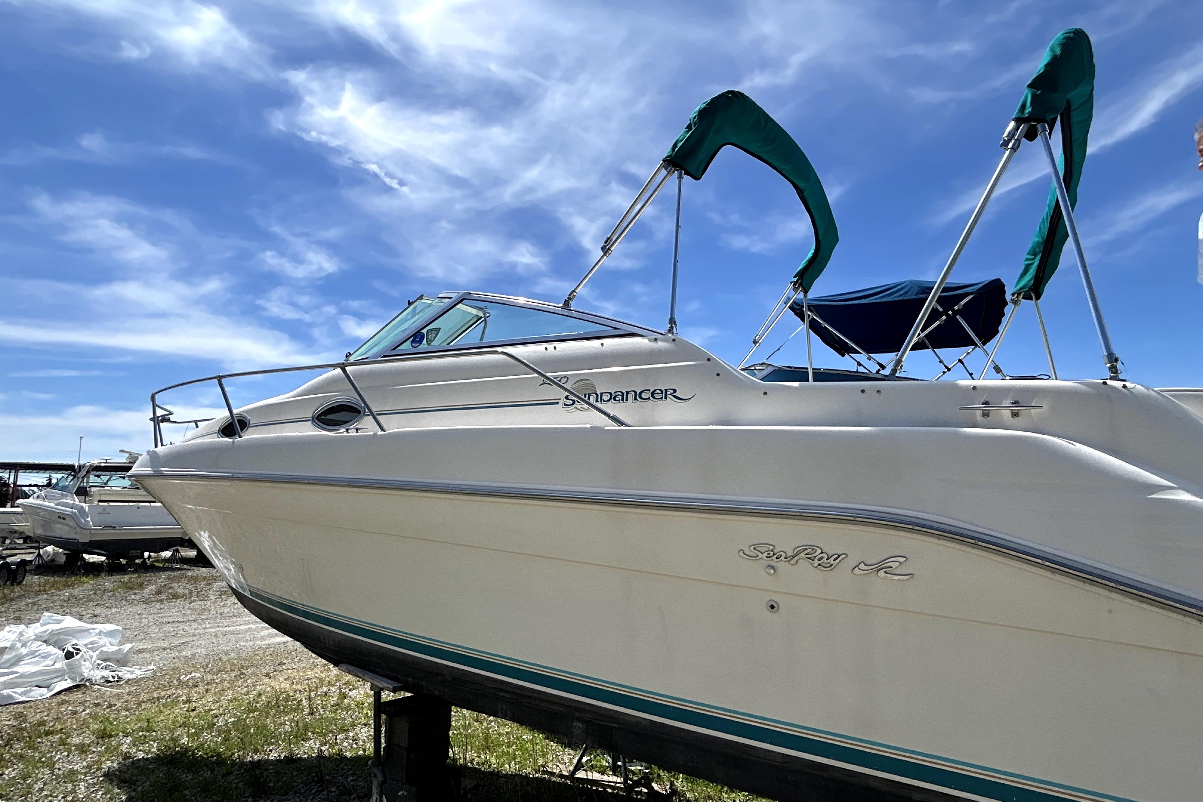 1995 Sea Ray 250 Sundancer boat on land under a clear blue sky.