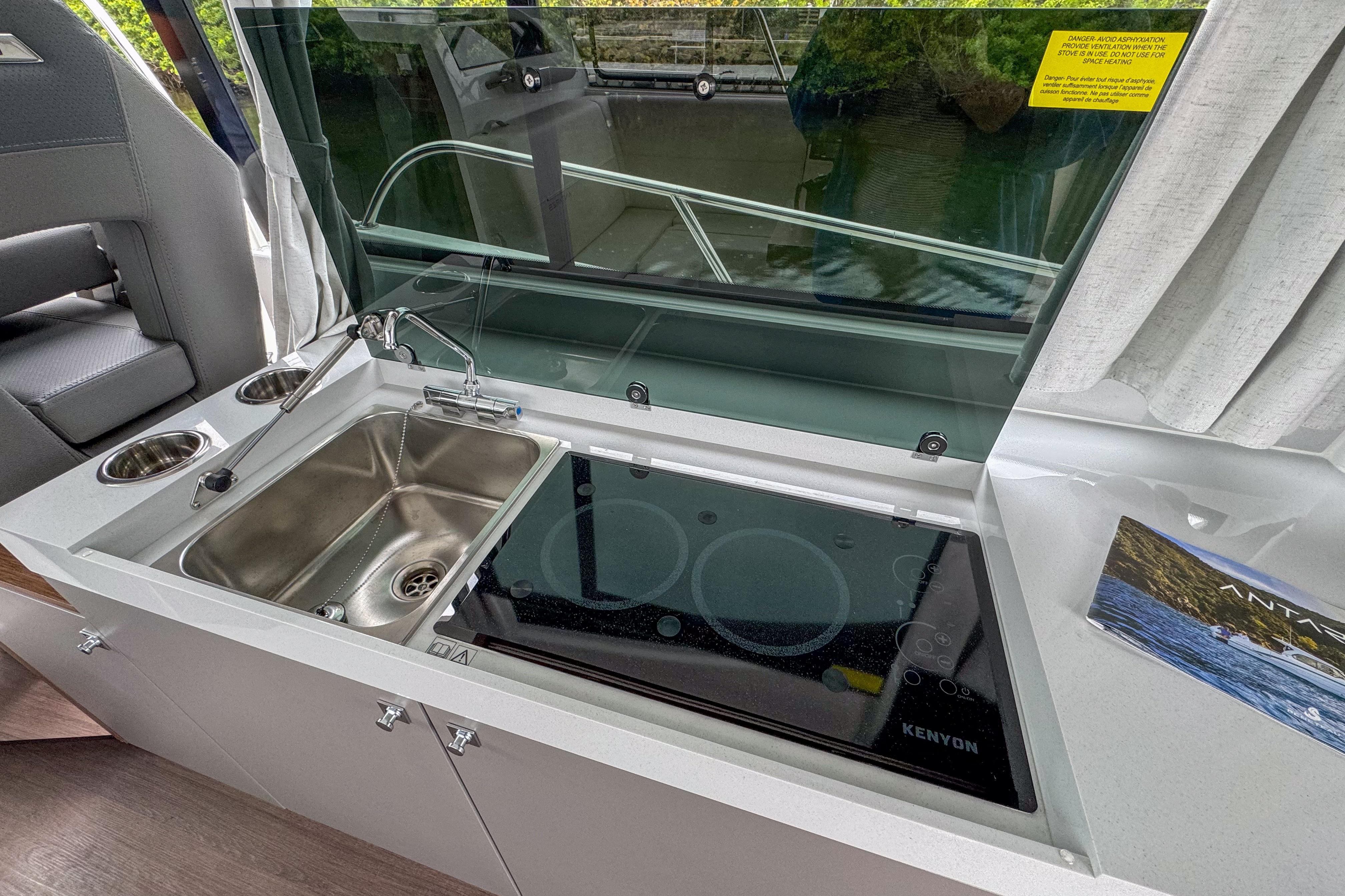 Modern kitchen area on 2026 Beneteau Antares 11 with sink and Kenyon cooktop.