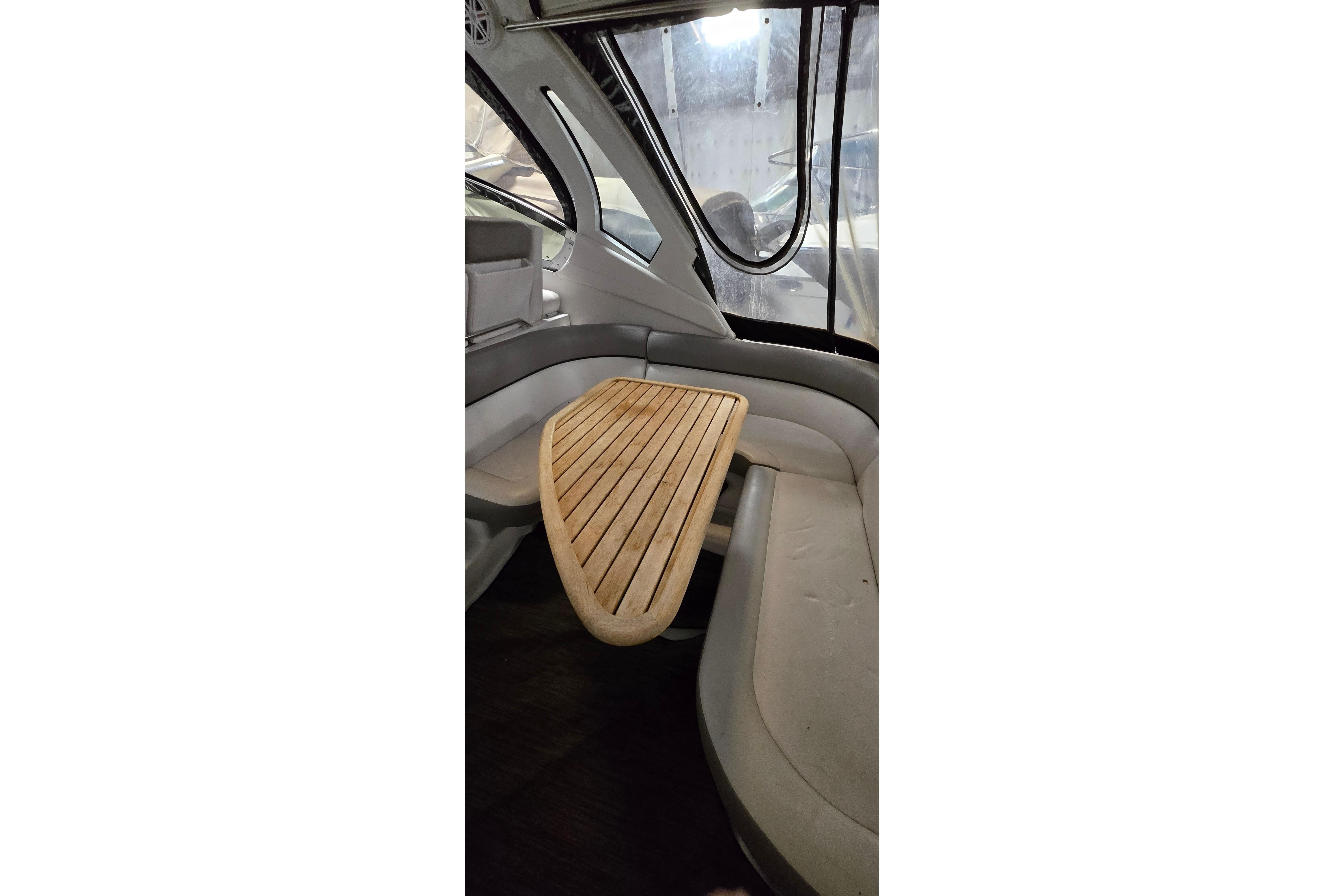 Interior of 2018 Four Winns V355 boat with wooden table and cushioned seating.