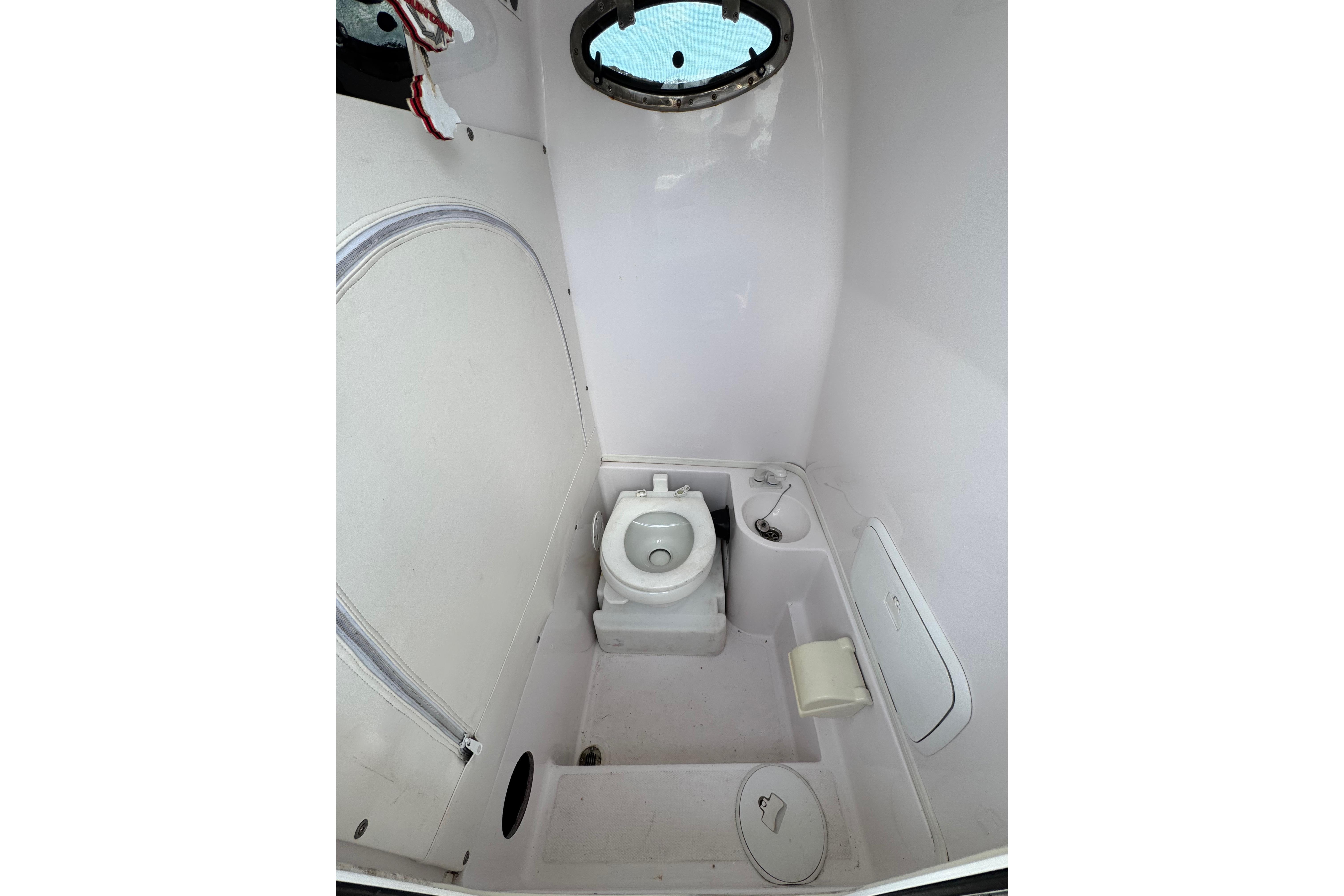 2018 Fountain 34 Center Console boat bathroom with toilet and porthole window.