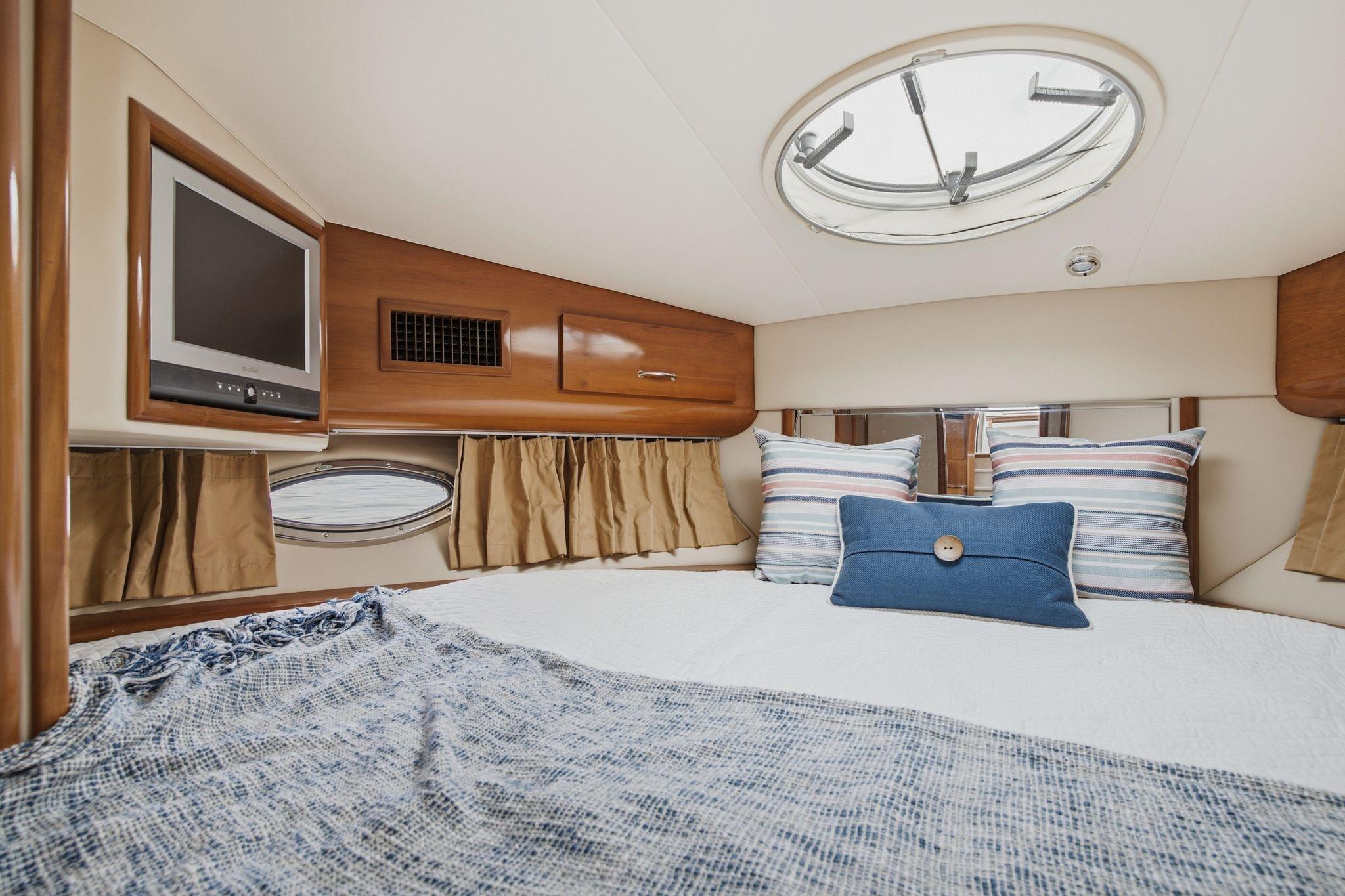 Luxurious 2005 Carver 39 Motor Yacht bedroom with cozy bedding and a mounted TV.