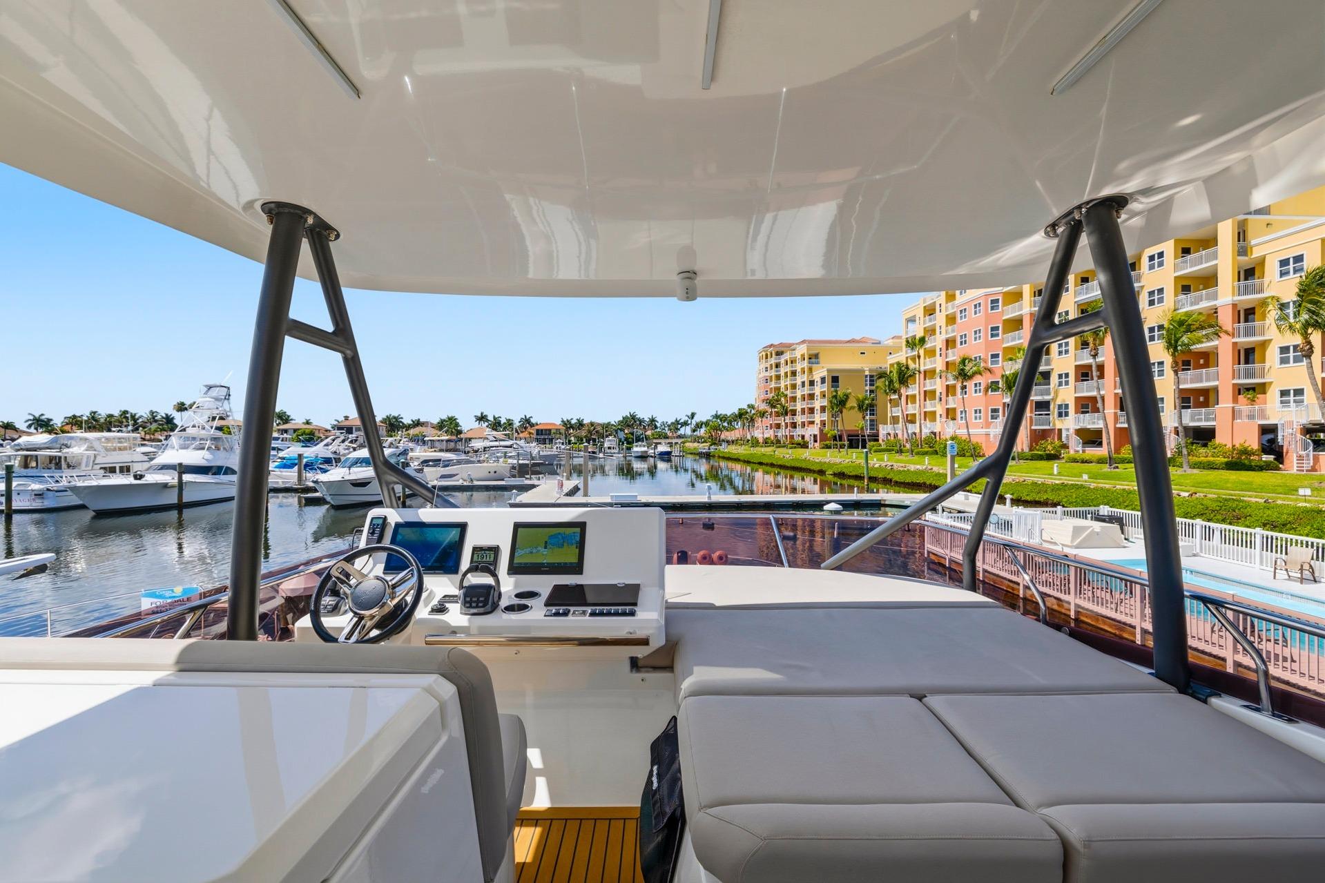 Flybridge view of 2022 Prestige 520 yacht docked at a marina with waterfront buildings.