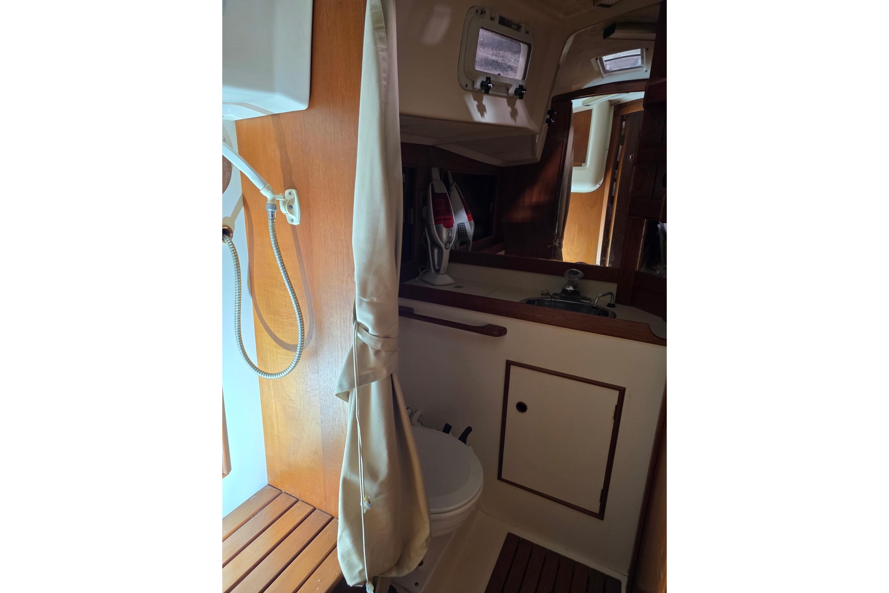 1985 Hinterhoeller Niagara 35 Encore yacht bathroom with shower and wooden accents.
