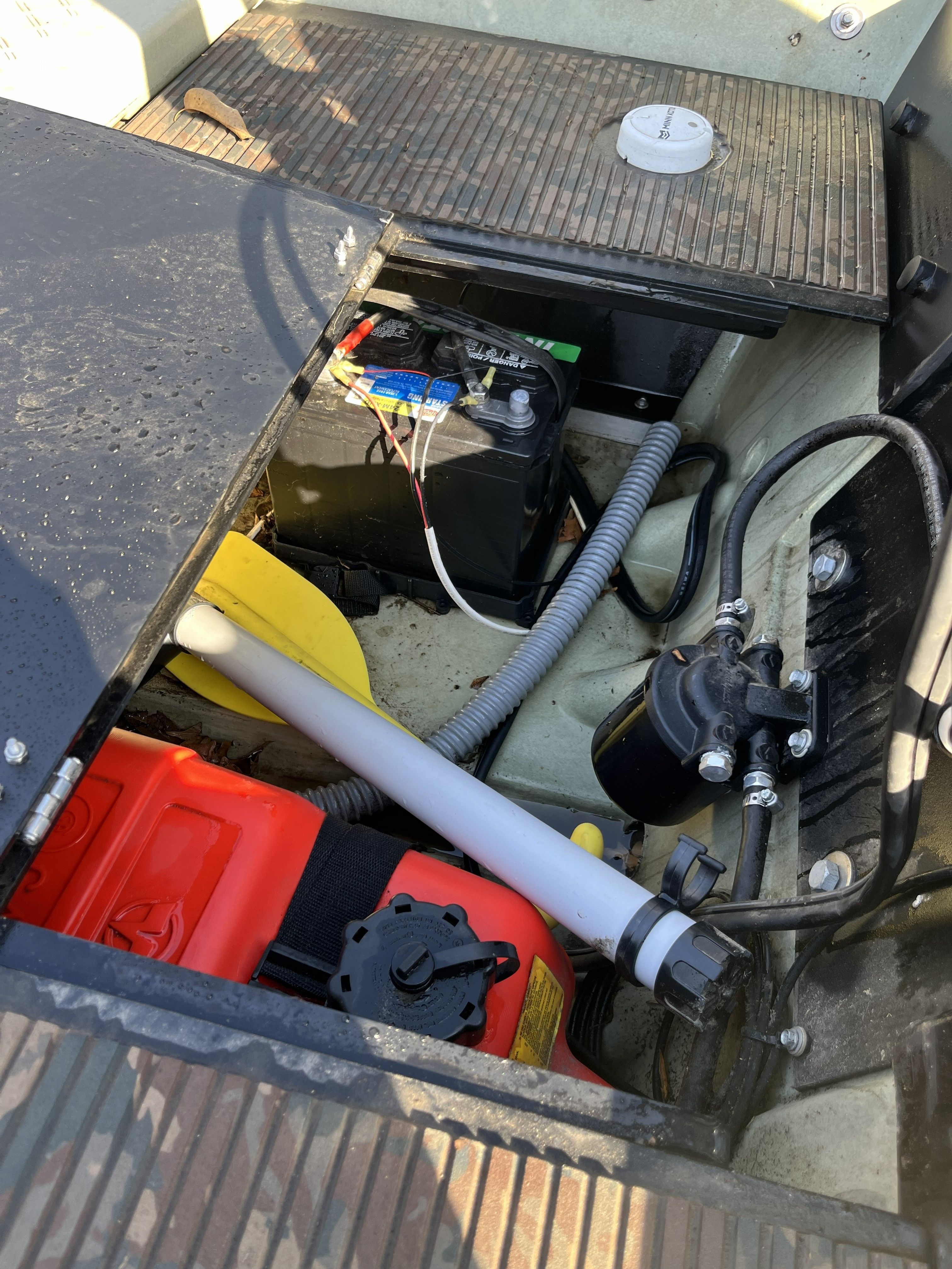 An open boat compartment reveals a battery, wiring, and other equipment.