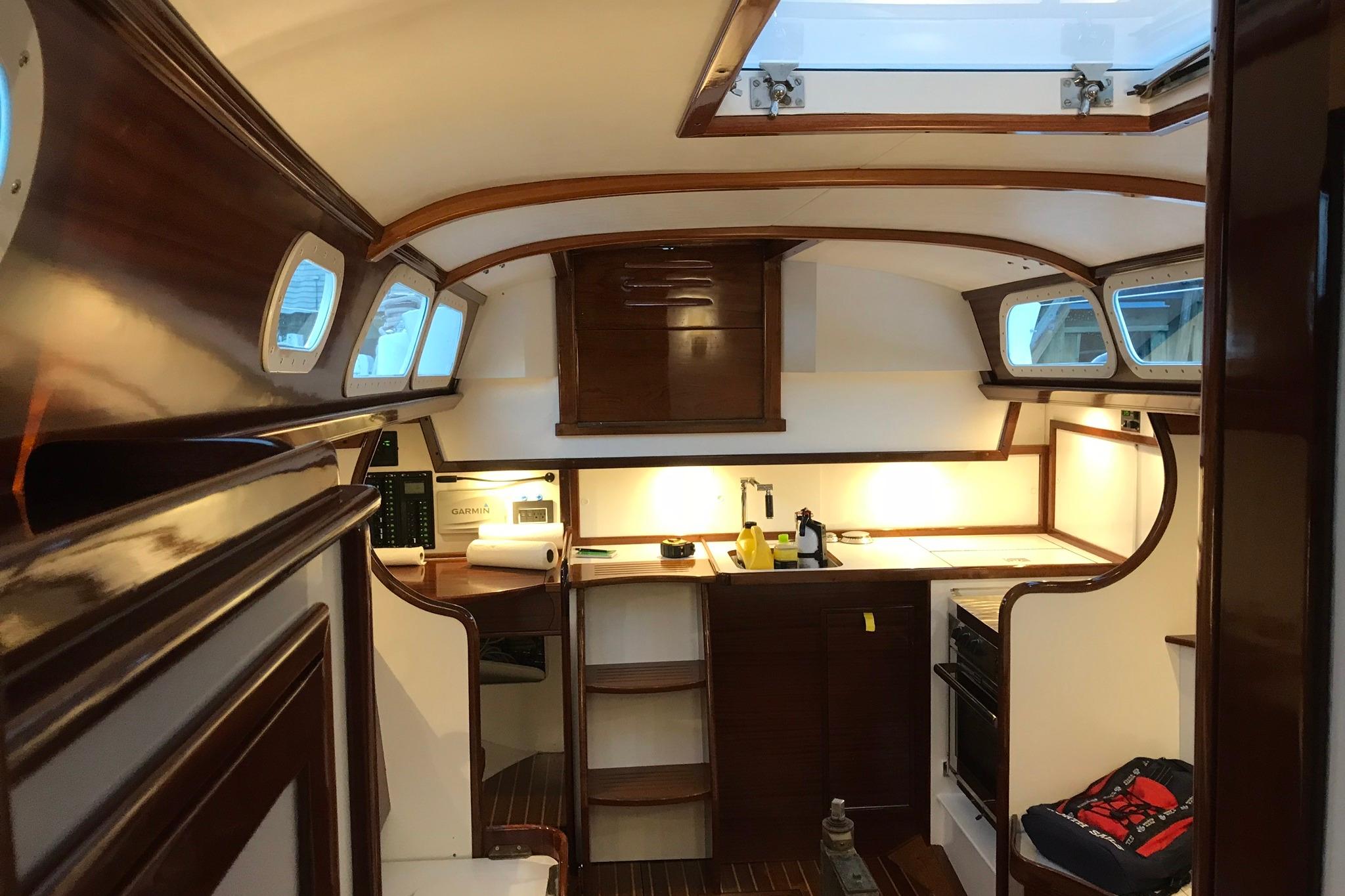 Interior of a 1970 Hinckley Bermuda 40 sailboat, featuring elegant wood finishes and a compact kitchen.