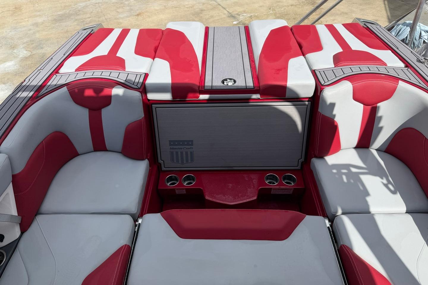 2023 MasterCraft X24 boat interior with red and gray seating and cup holders.