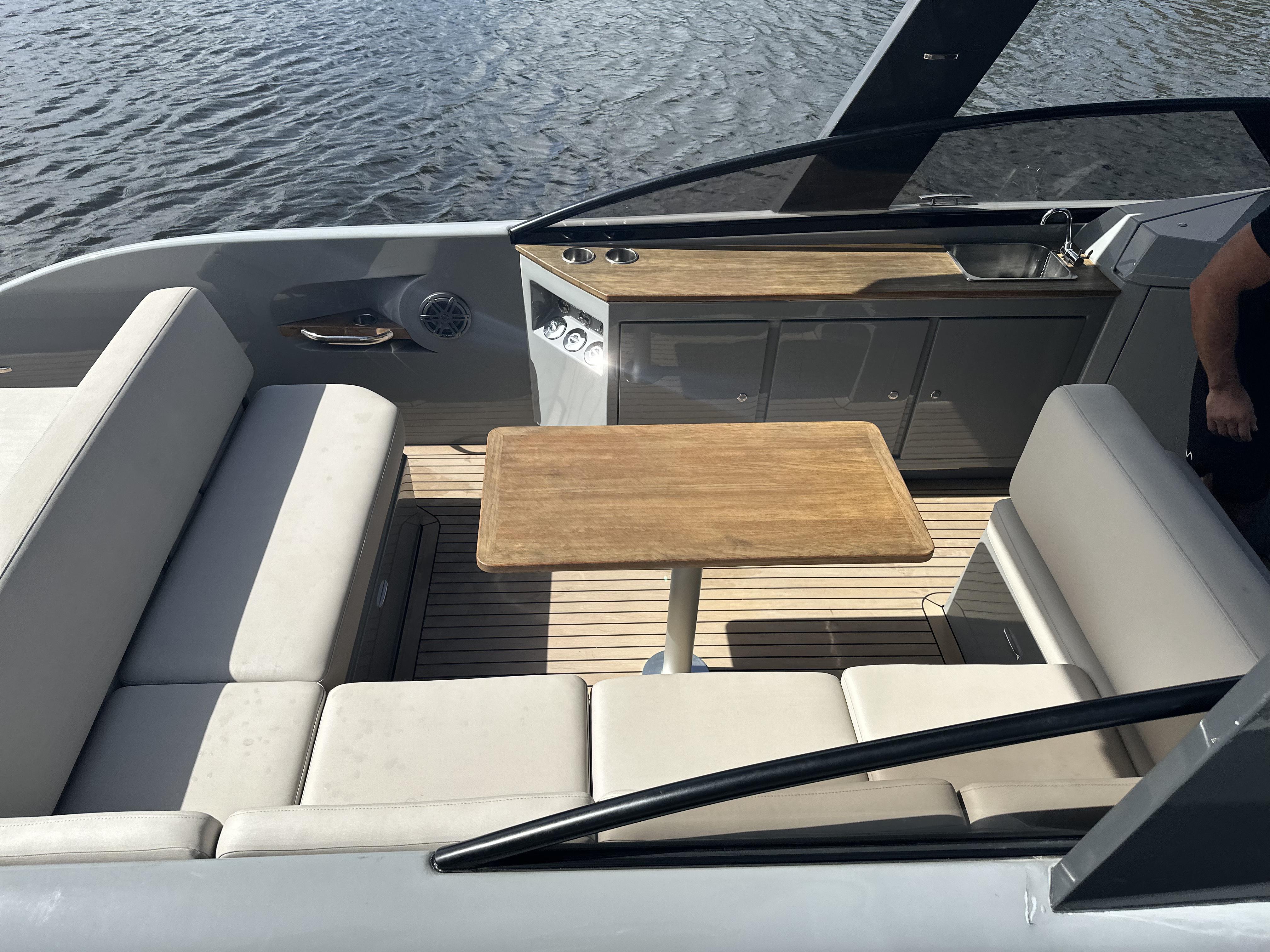 2021 Rand Leisure boat interior with seating, table, and kitchenette on calm water.