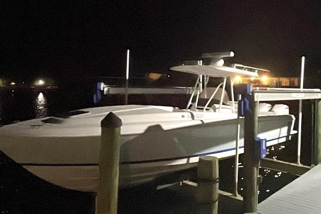 2002 Intrepid 323 Cuddy boat docked at night, illuminated by nearby lights.