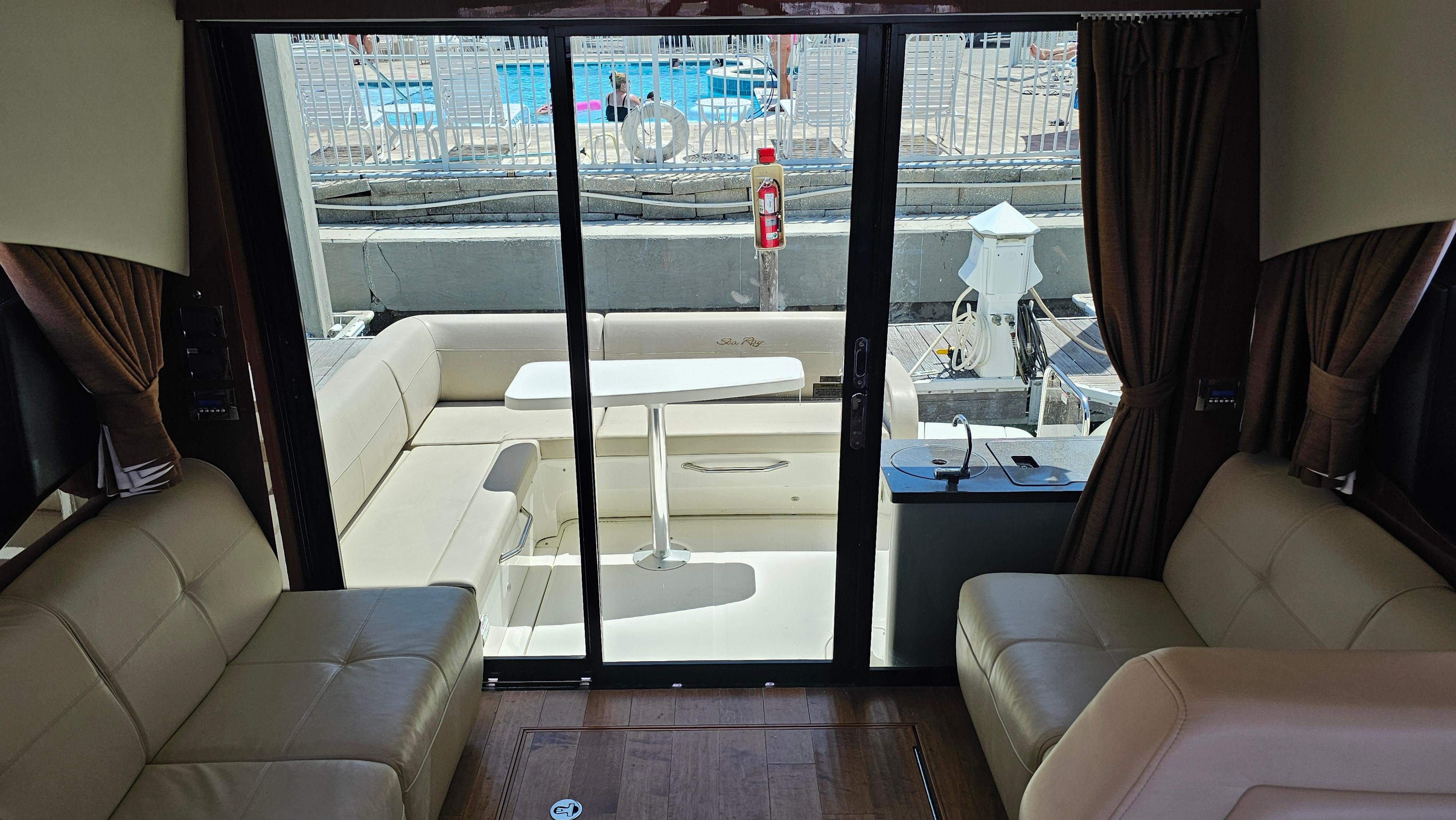 Interior view of 2016 Sea Ray 470 Sundancer yacht with beige seating and glass doors.