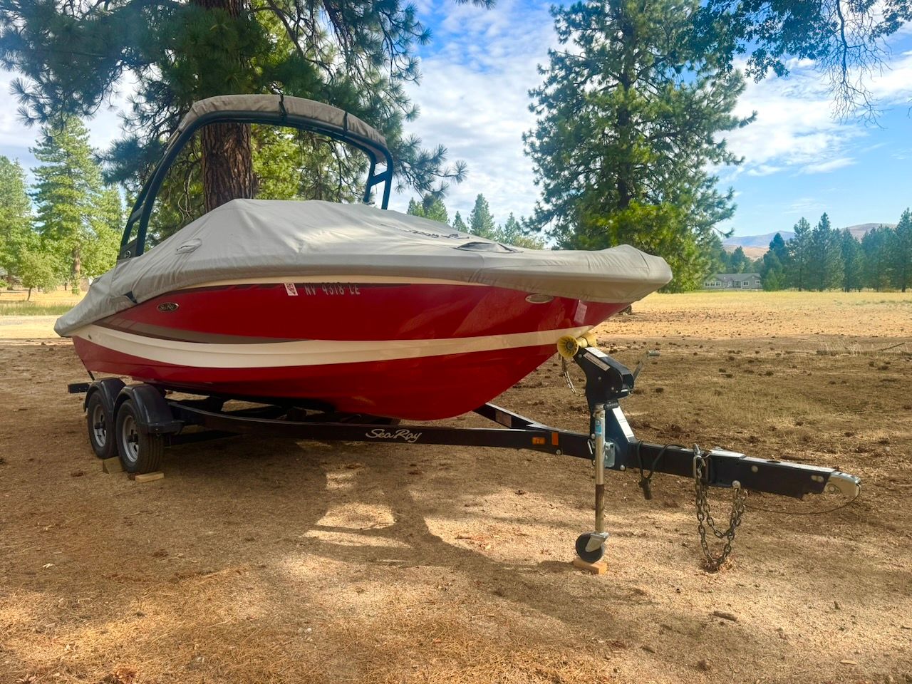 A red 2016 Sea Ray SPX 190 Outboard boat on a trailer outdoors.