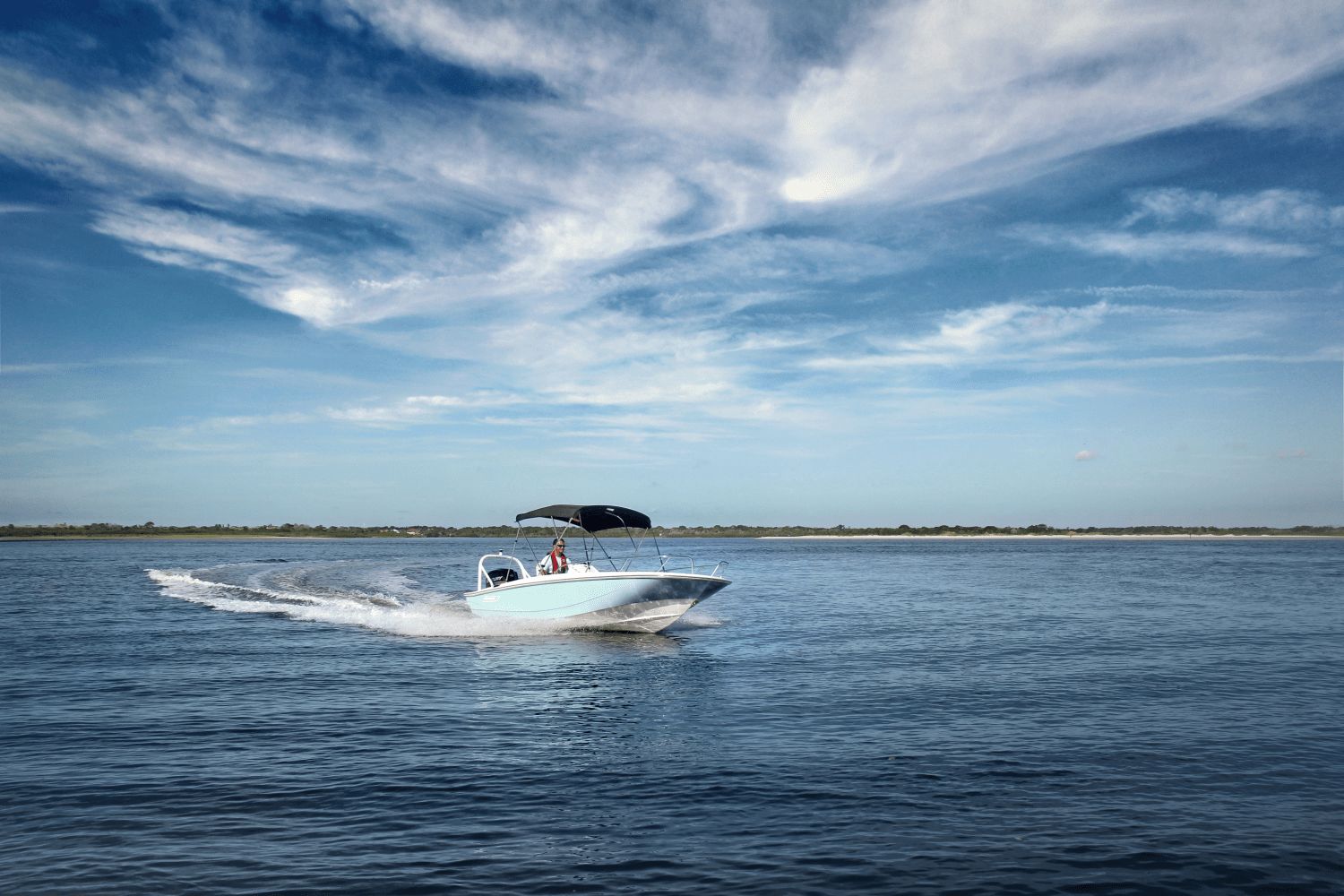 A 2026 Boston Whaler 160 Super Sport cruising on calm water under a blue sky.