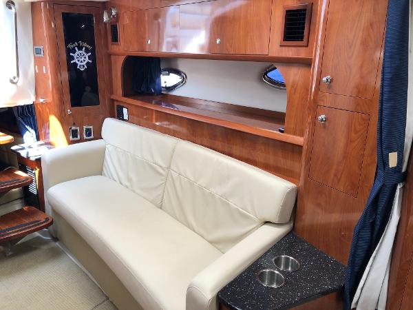 Interior of the 2008 Four Winns V338 with cream sofa and wooden cabinetry.