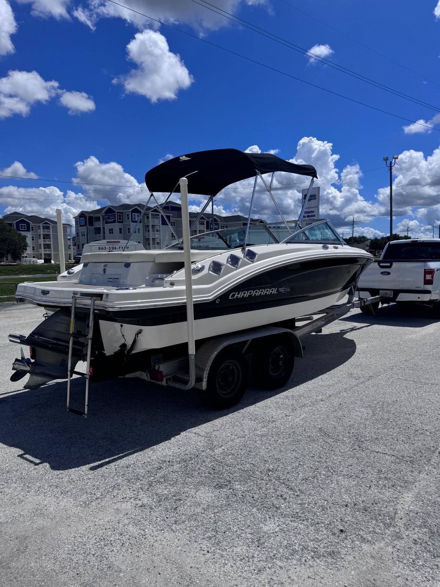 2013 Chaparral 206 SSi on a trailer, with a bimini top, in front of a residential complex.
