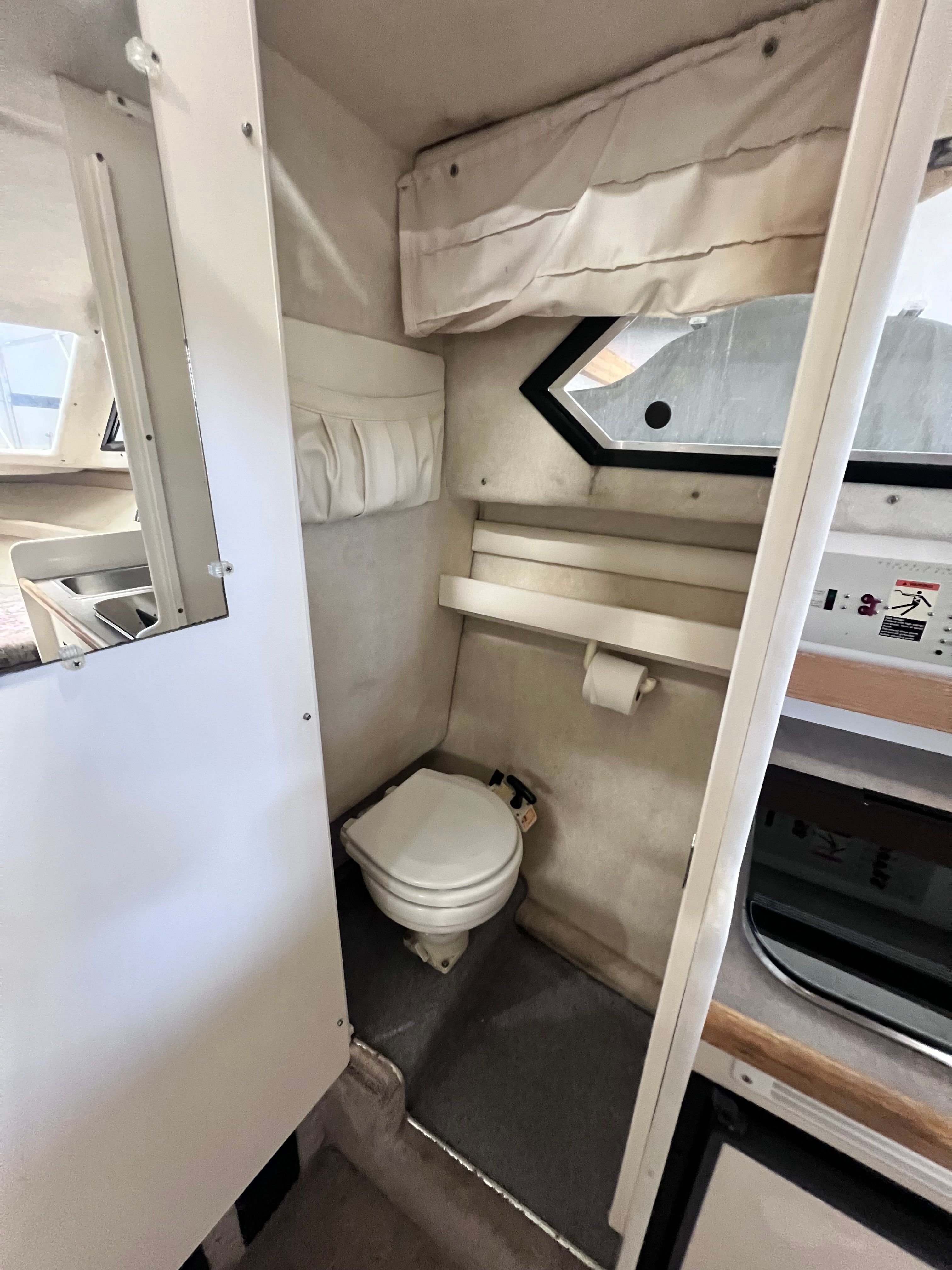 Interior of a 1997 Bayliner 2452 with toilet and window.