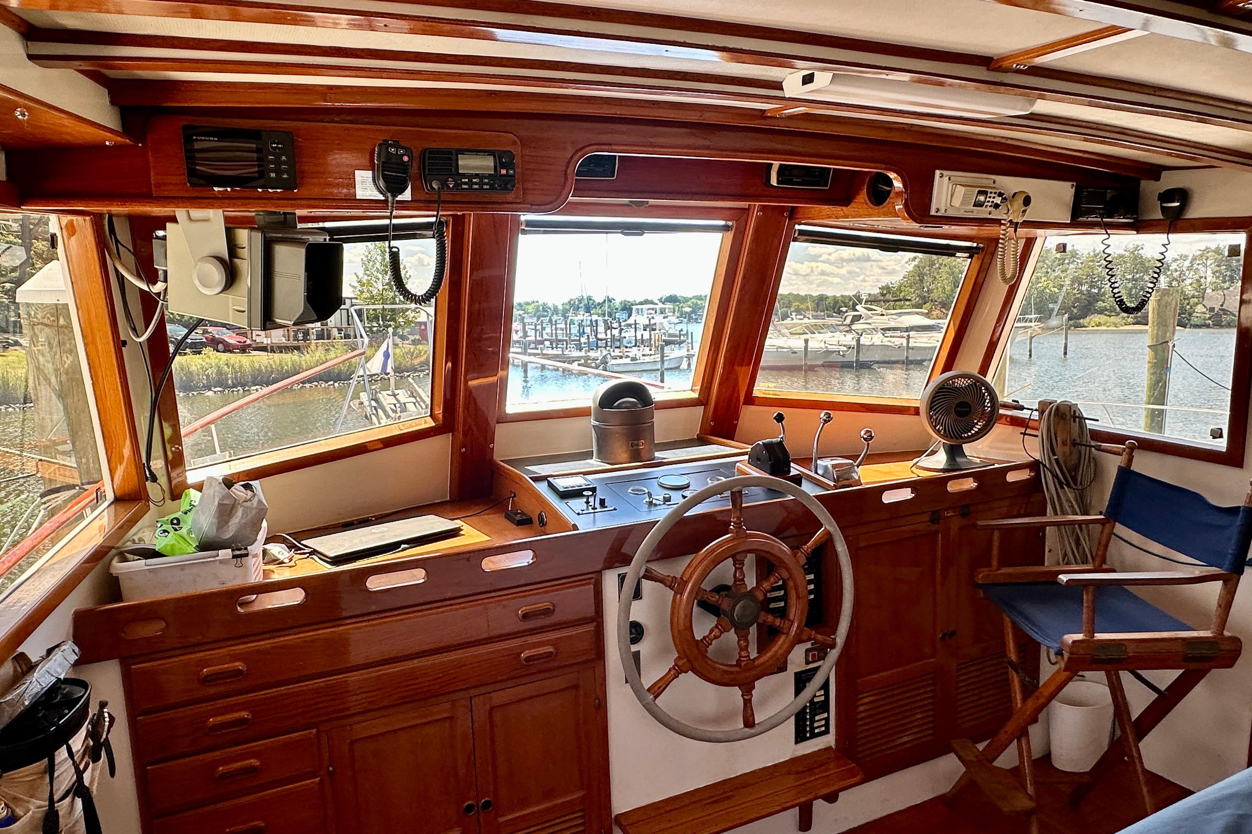 1983 Kadey-Krogen Krogen 42 Trawler helm with wooden wheel, overlooking marina.