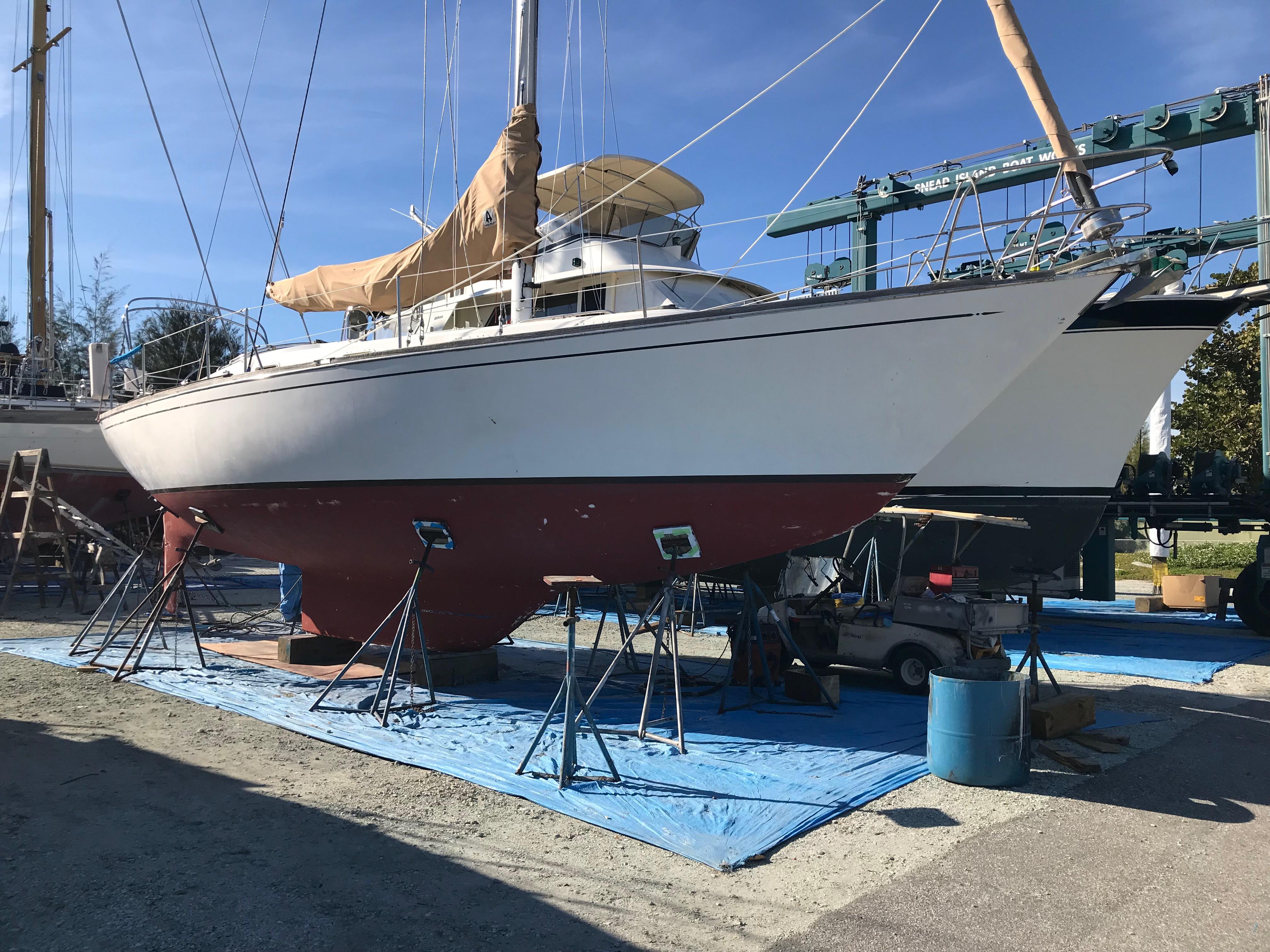 1981 Tartan 37 sloop sailboat on stands in a boatyard under clear blue sky.