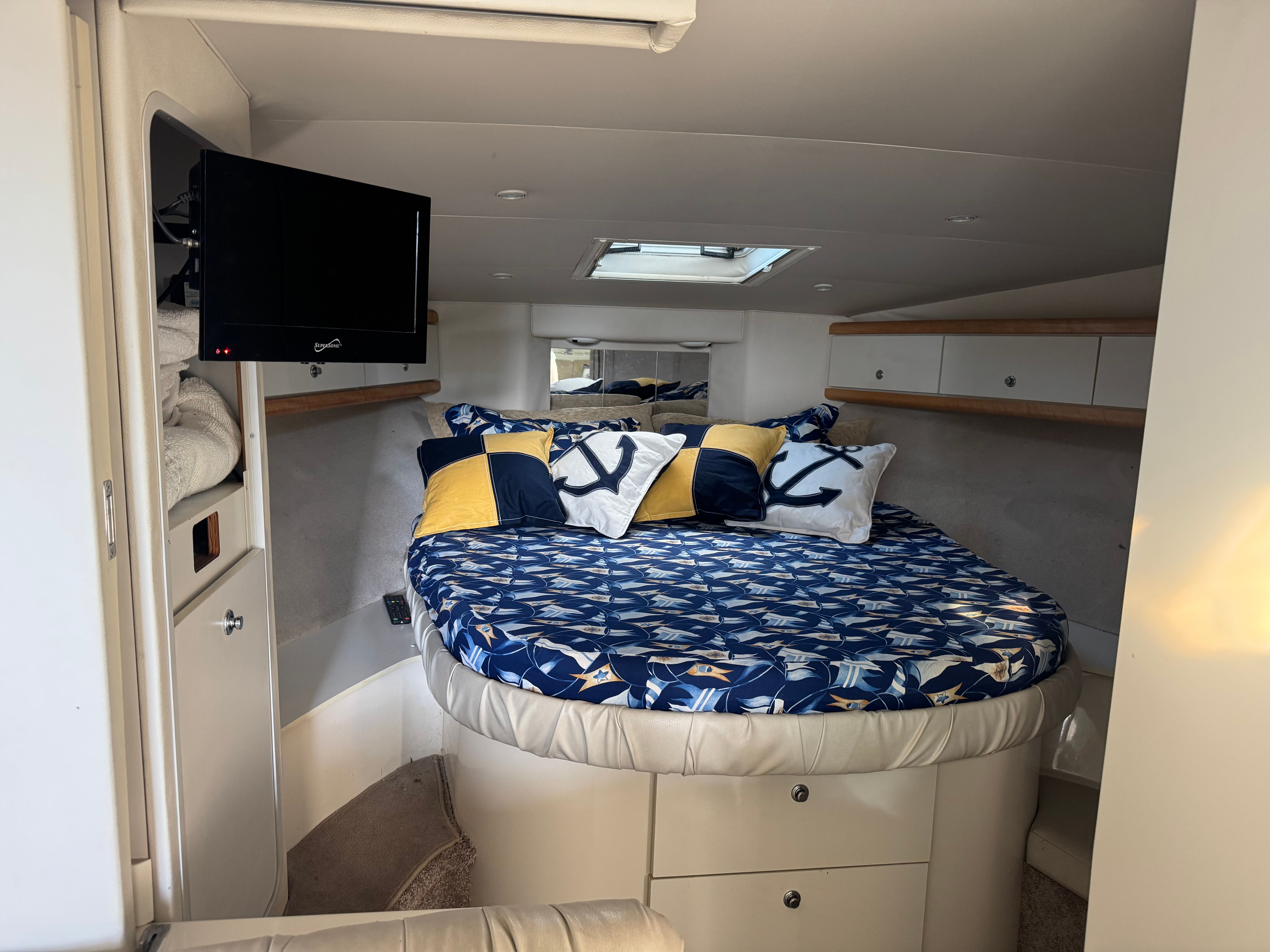 Interior of a 1995 Trojan 390x with a cozy bed, blue pillows, and a TV.