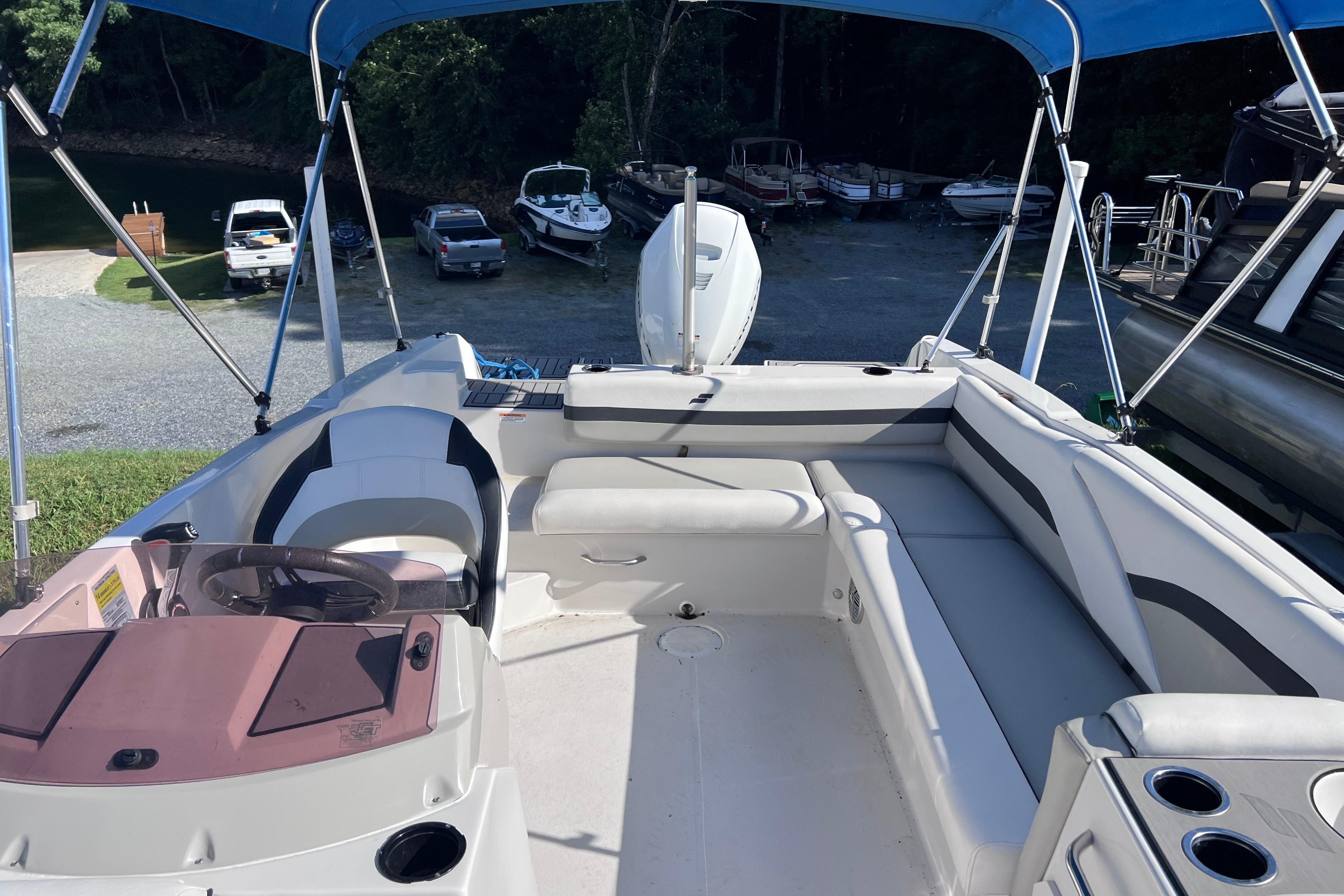 2021 Starcraft SVX 211 OB boat interior with seating and steering wheel under blue canopy.