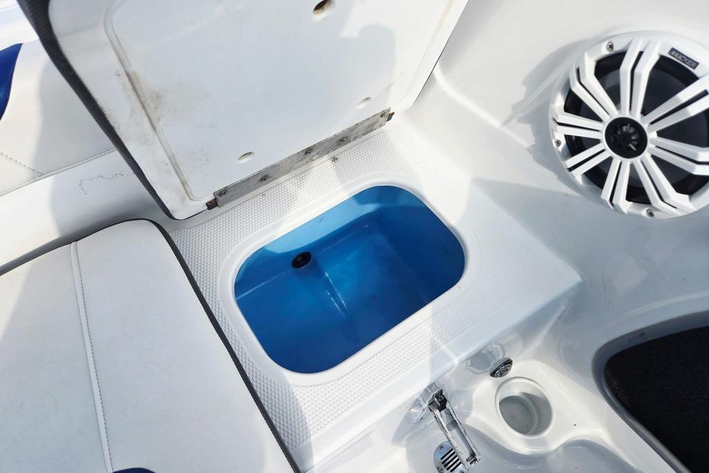 Open storage compartment in 2018 Tahoe 450 TS boat with speaker and cup holder.