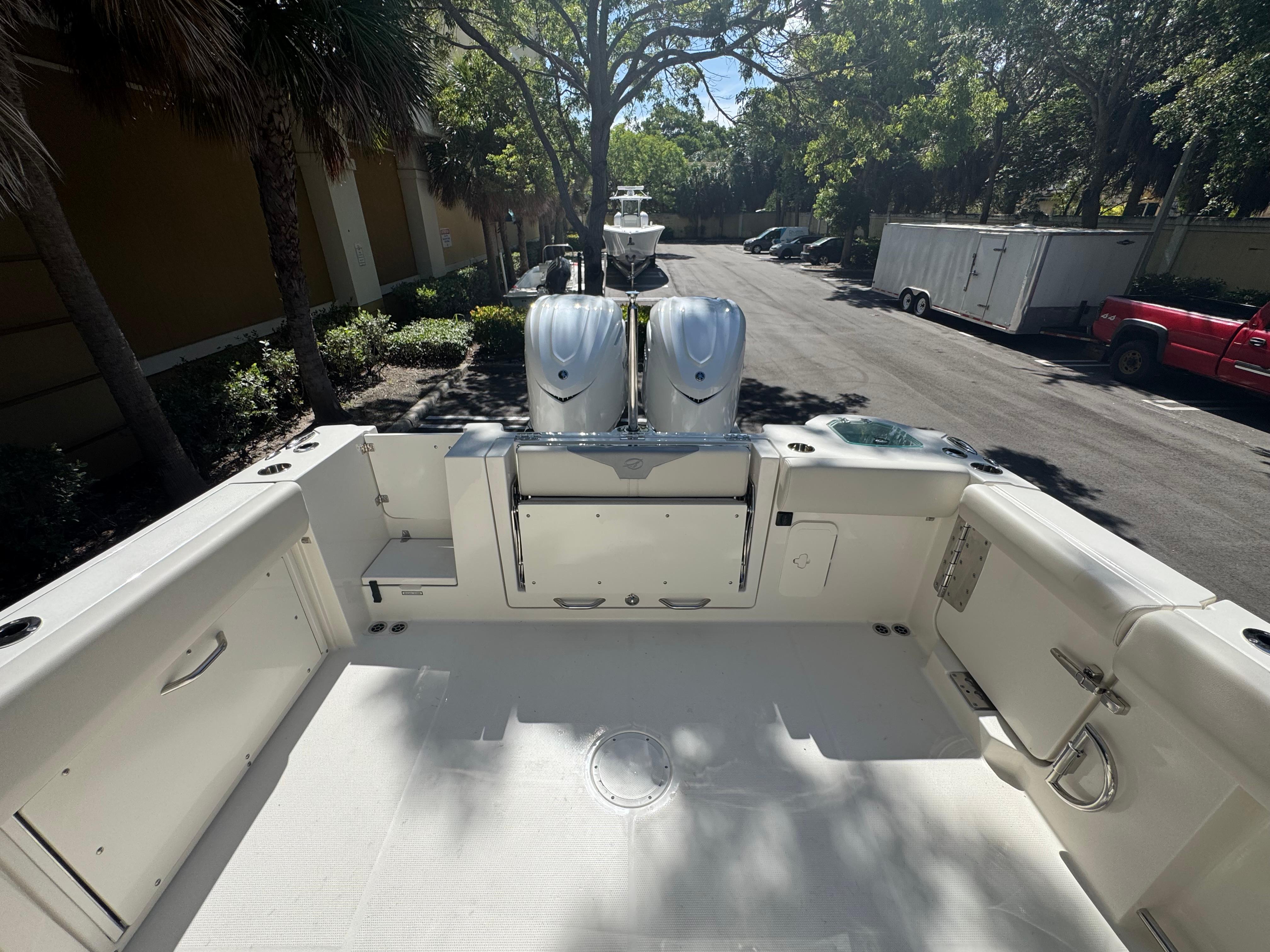 2026 Sailfish 312 CC boat deck with dual engines, parked outdoors under trees.