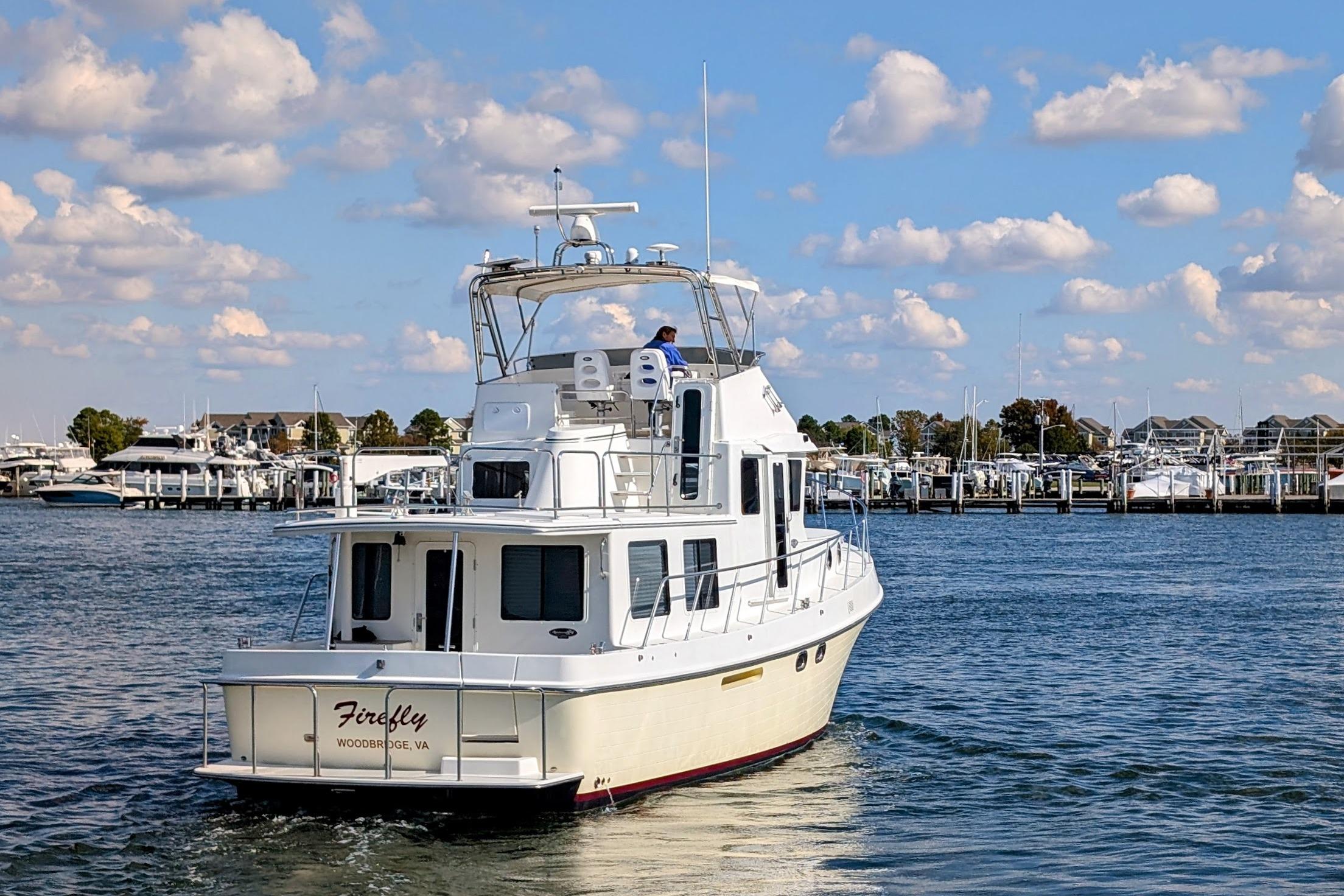 2015 American Tug 435 cruising in a marina under a blue sky.