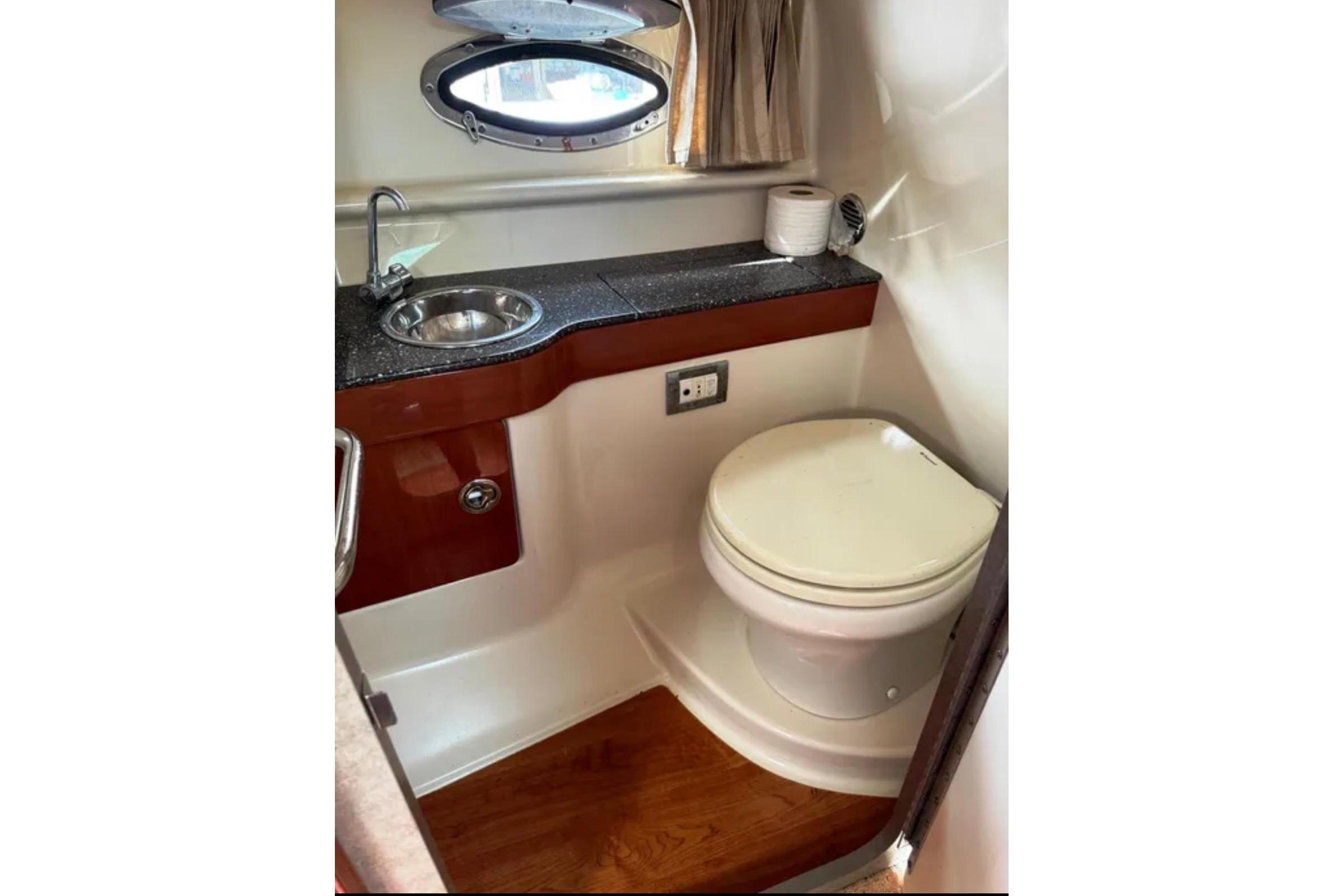 2010 Formula 310 Sun Sport boat bathroom with sink, toilet, and porthole window.