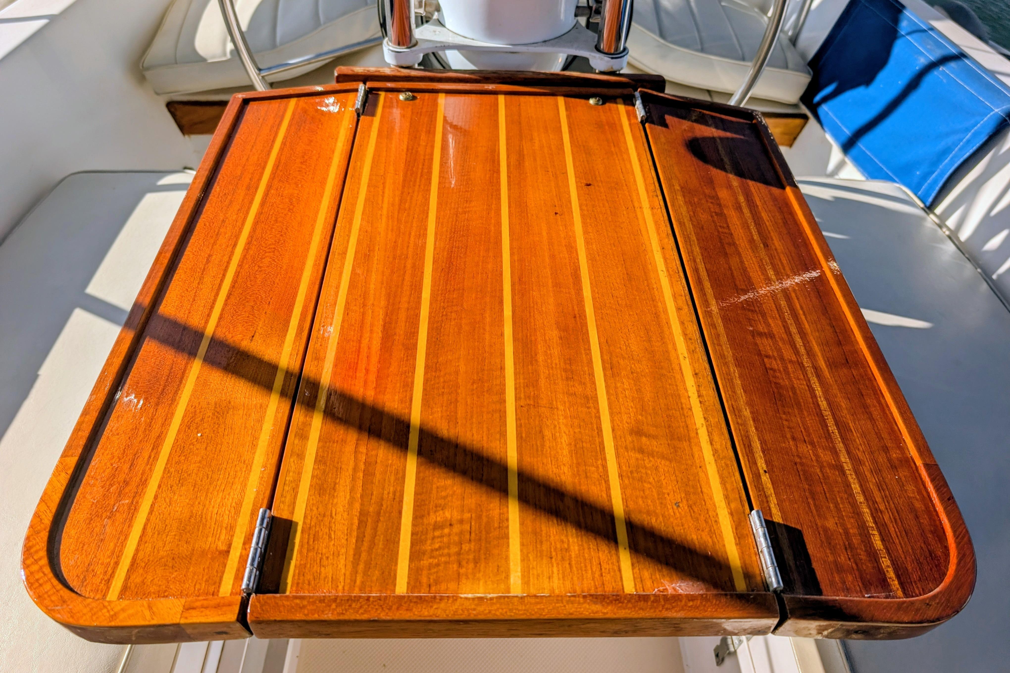 Polished wooden table on a 1989 Catalina 34 sailboat, reflecting sunlight.
