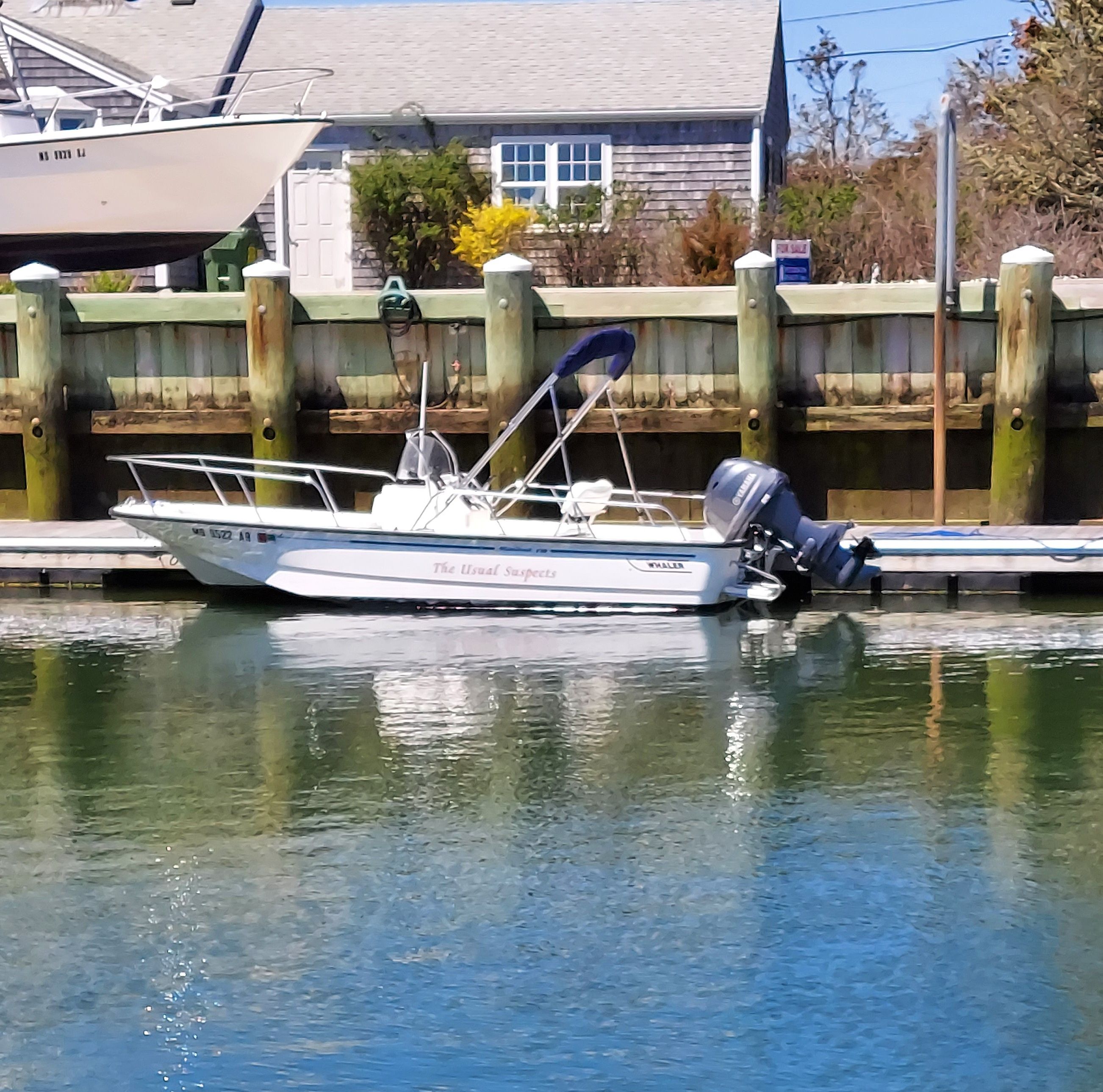 A 2003 Boston Whaler 170 Montauk is docked at a calm pier.
