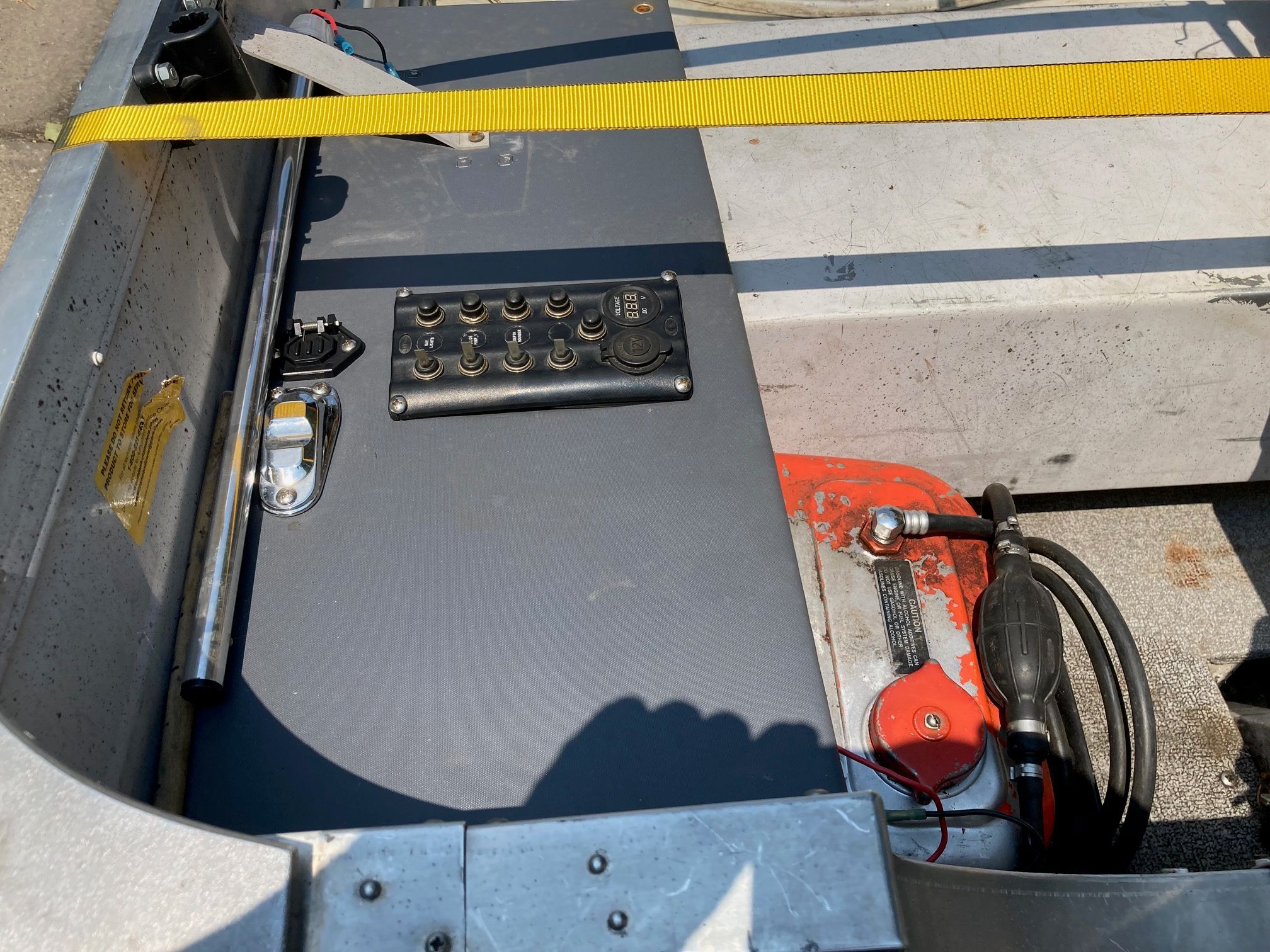 A boat with a control panel and yellow strap, partially in shadow.