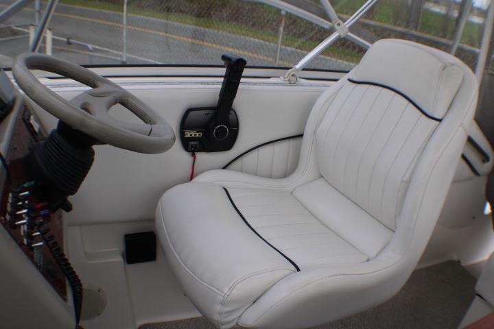 1998 Bayliner 2655 Ciera Sunbridge cockpit with white captain's chair and steering wheel.