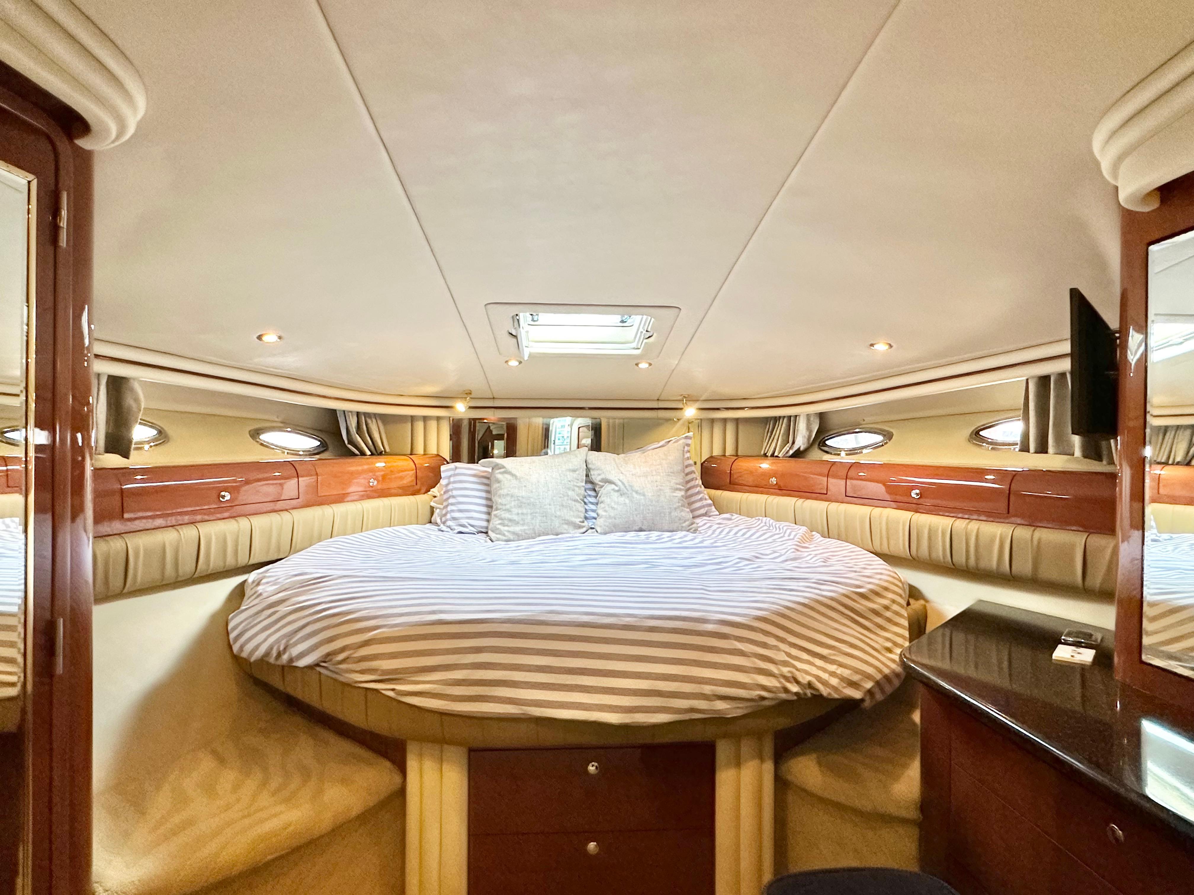 Luxurious bedroom interior of 2002 Sea Ray 560 Sedan Bridge yacht with striped bedding.