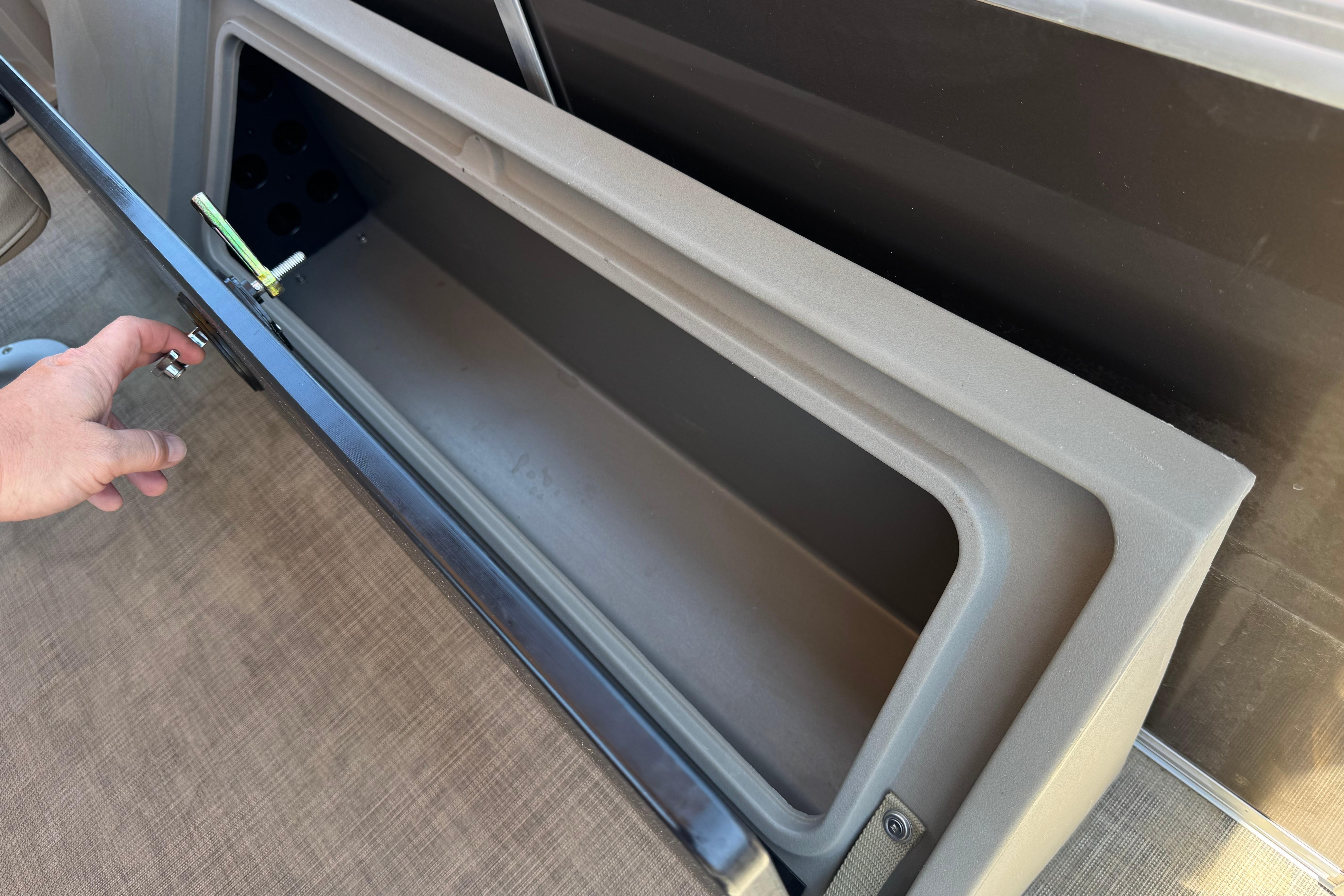 Storage compartment on 2024 Sun Tracker SportFish 22 DLX boat, open with hand accessing.