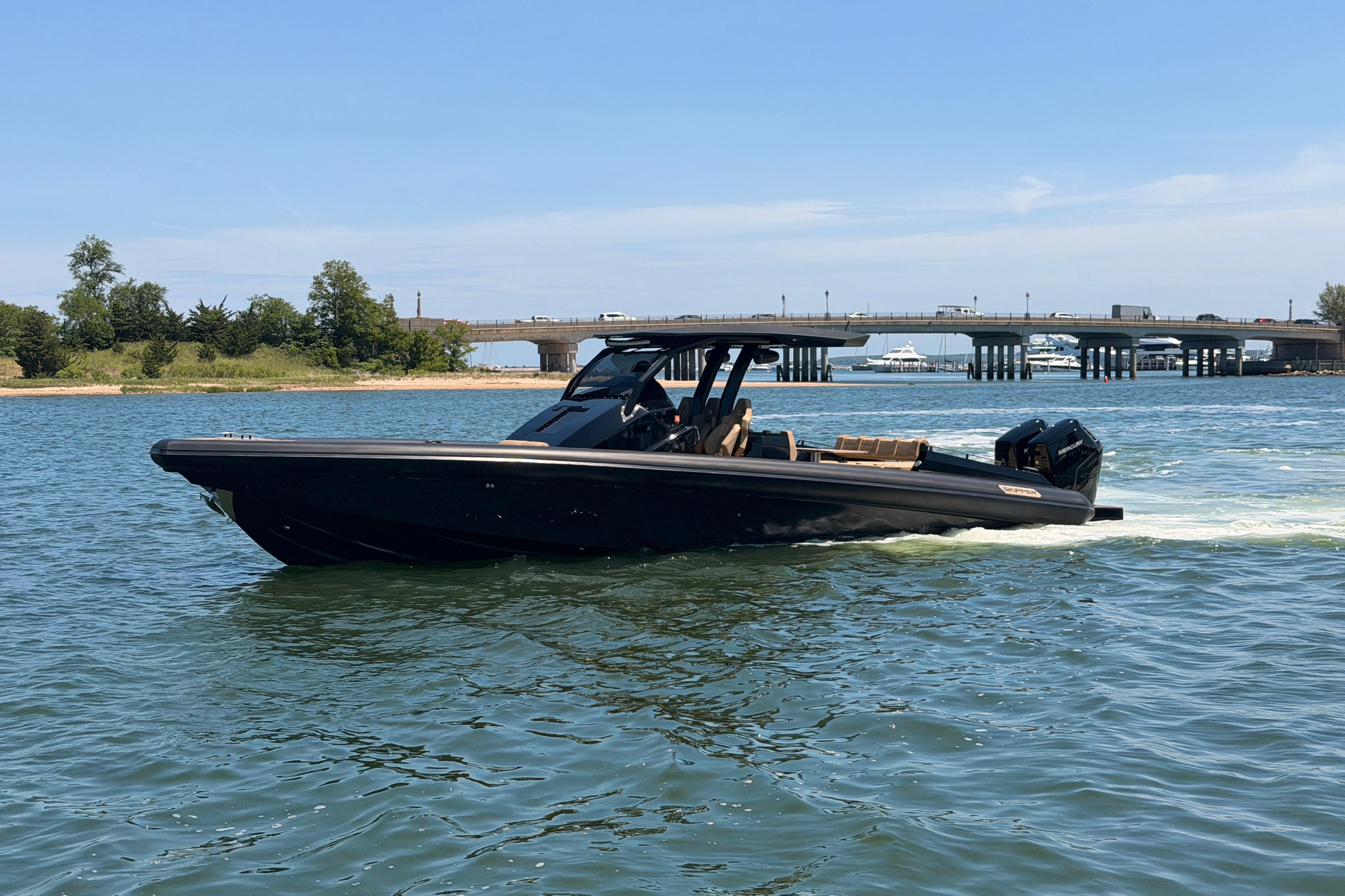2023 Skipper-BSK 42NC boat cruising on a sunny day near a bridge.