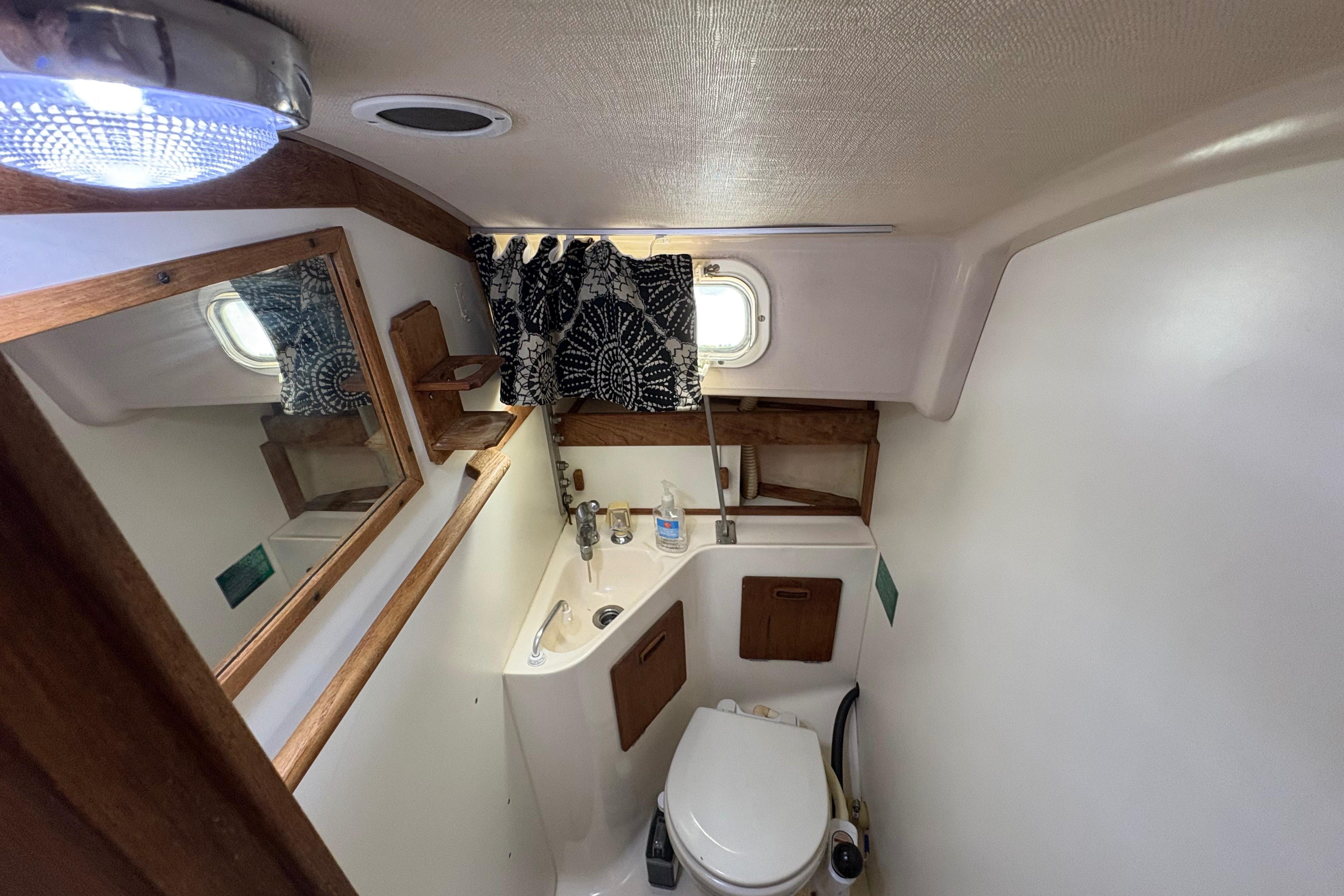 1981 Sabre 31 yacht bathroom with sink, toilet, mirror, and window.