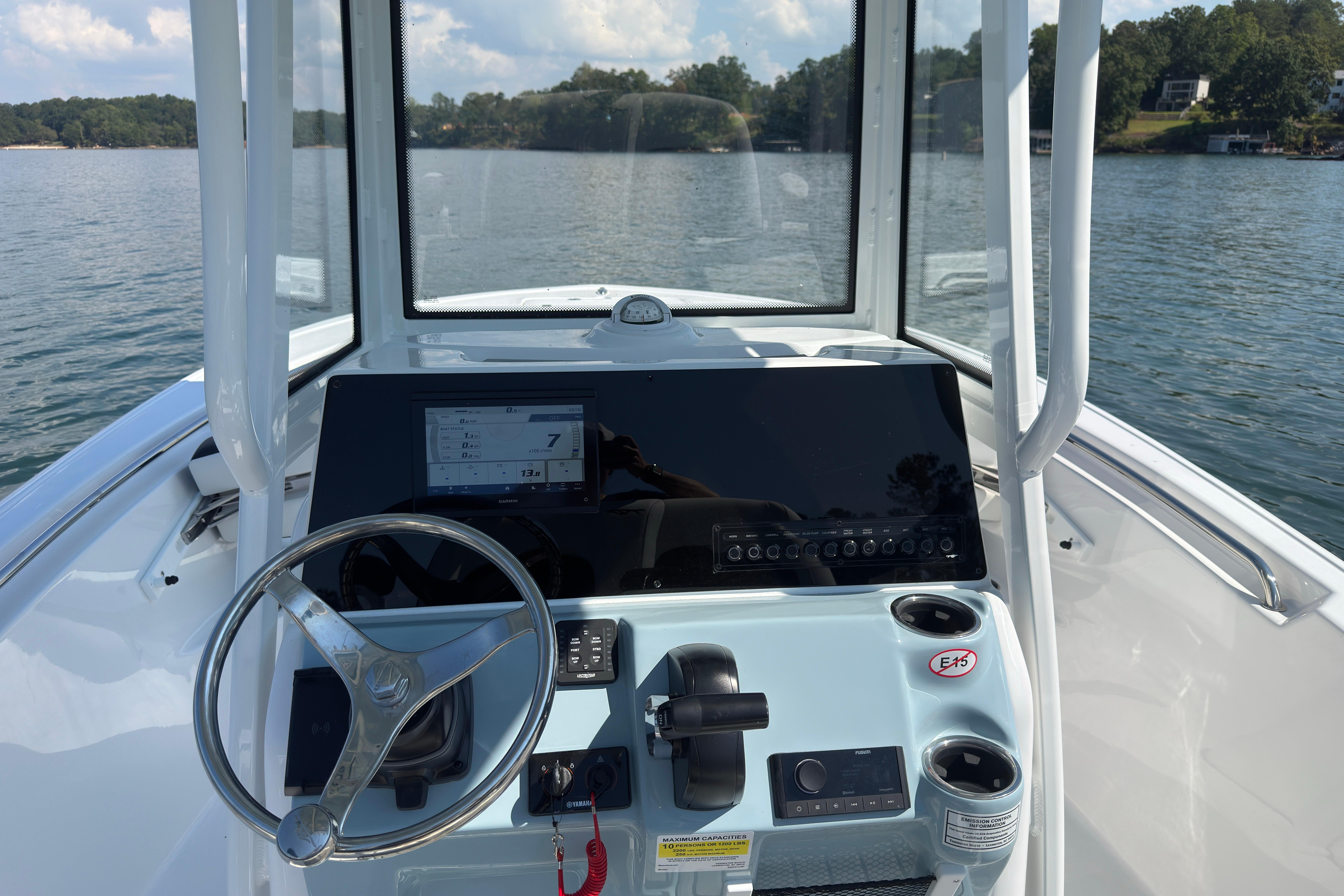 2026 Tidewater 220 LXF boat dashboard with steering wheel and control panel on a lake.