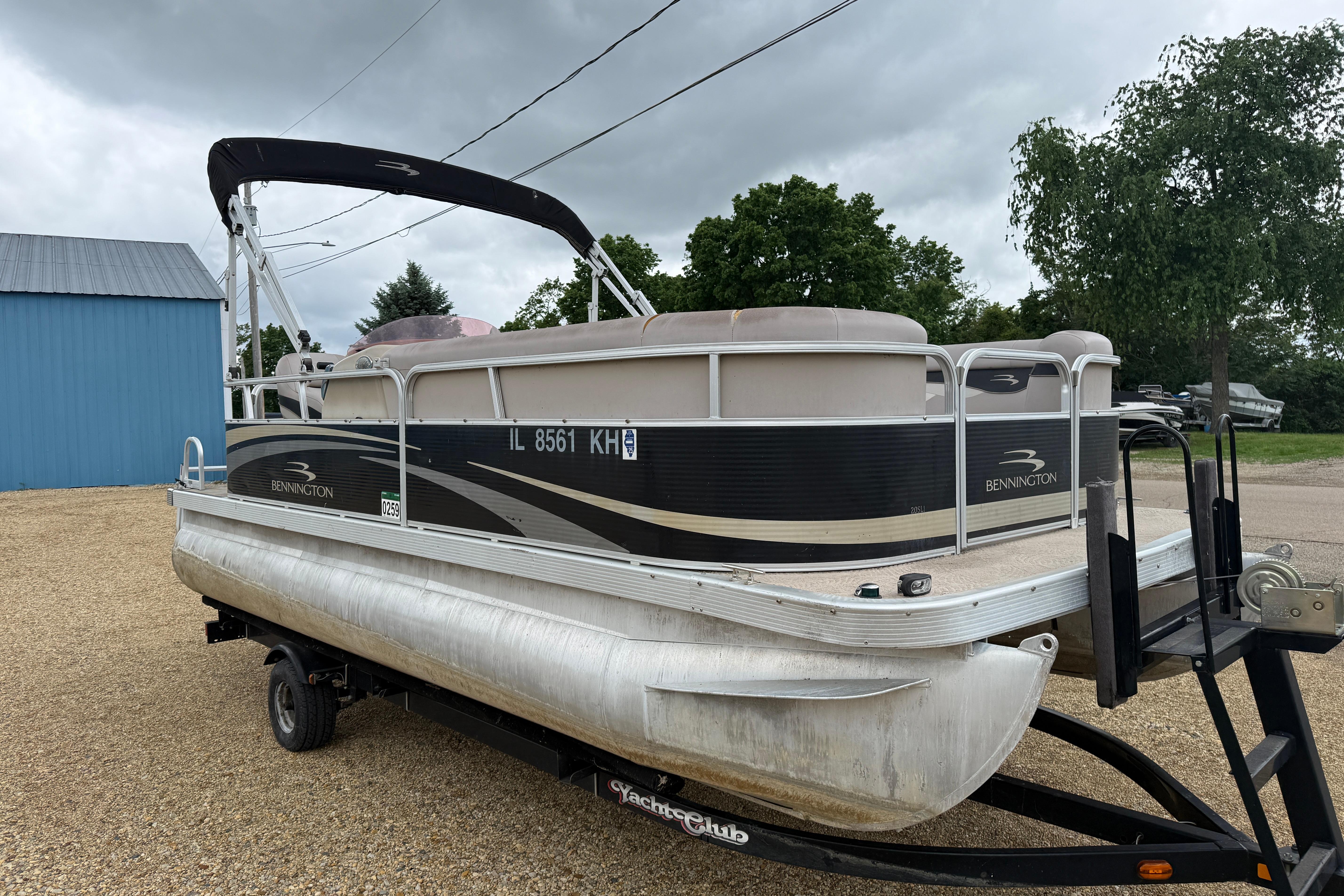 2010 Bennington 20SLi pontoon boat on trailer, parked outdoors under cloudy sky.
