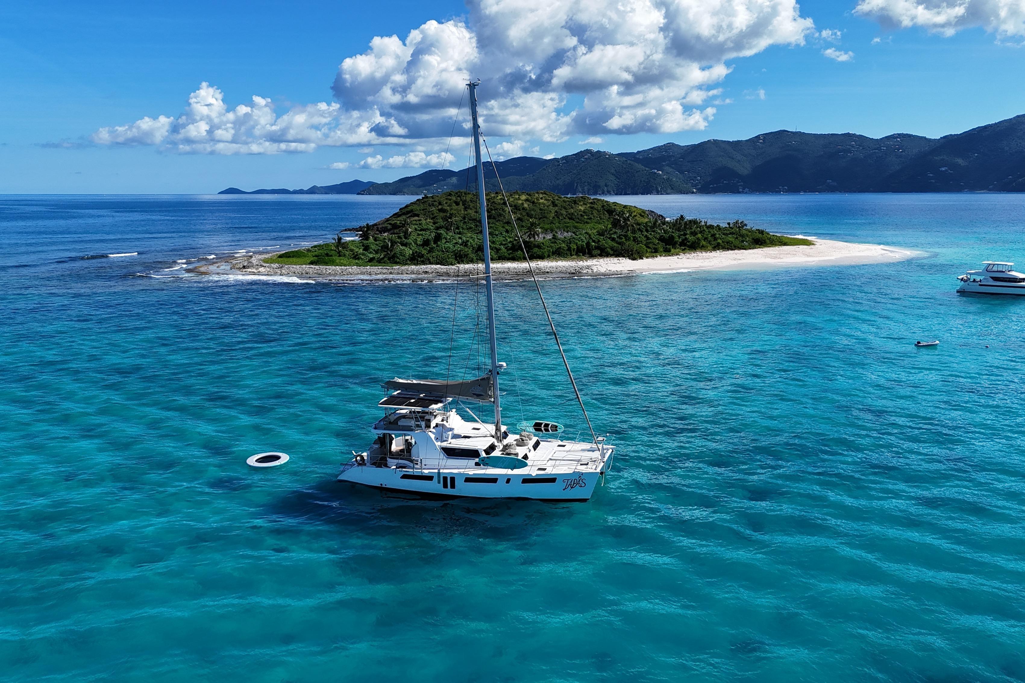 2023 Royal Cape Catamarans 570 Majestic sailing near tropical island in clear blue waters.