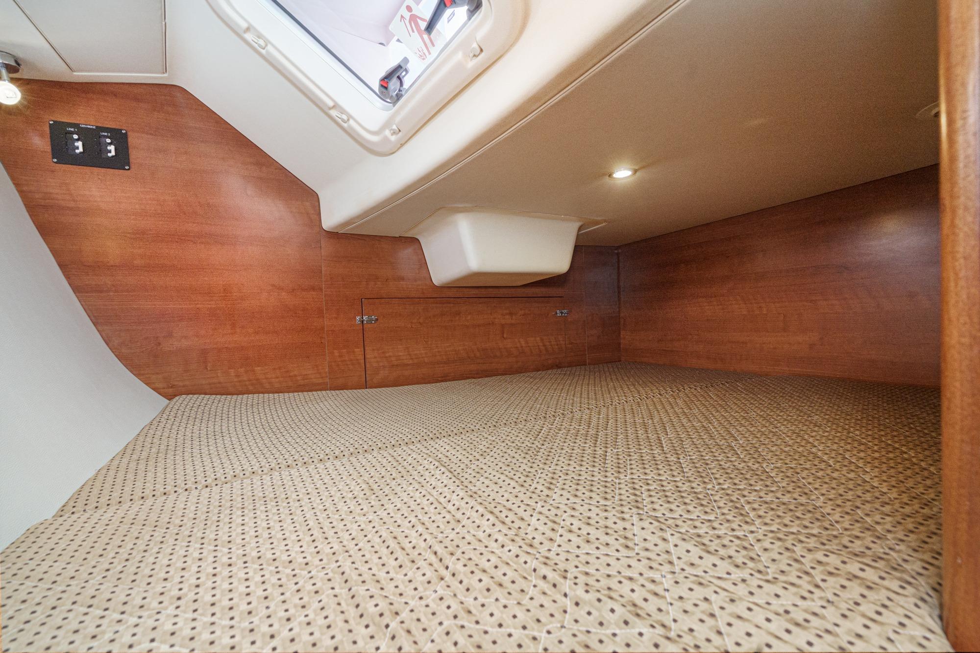 Interior cabin of 2015 Hunter 33 sailboat with wood paneling and patterned bedding.