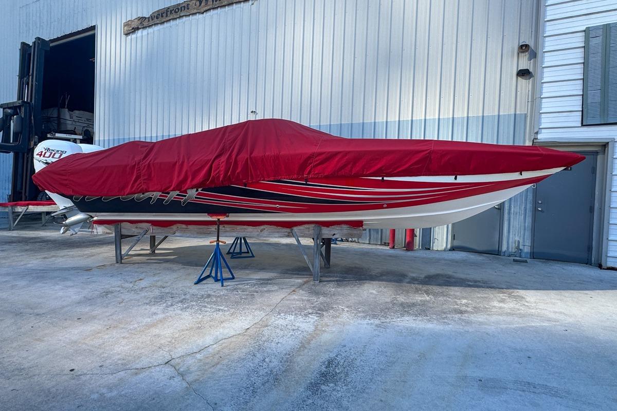 2022 Velocity 290sc boat covered in red tarp, stored on stands outside a building.