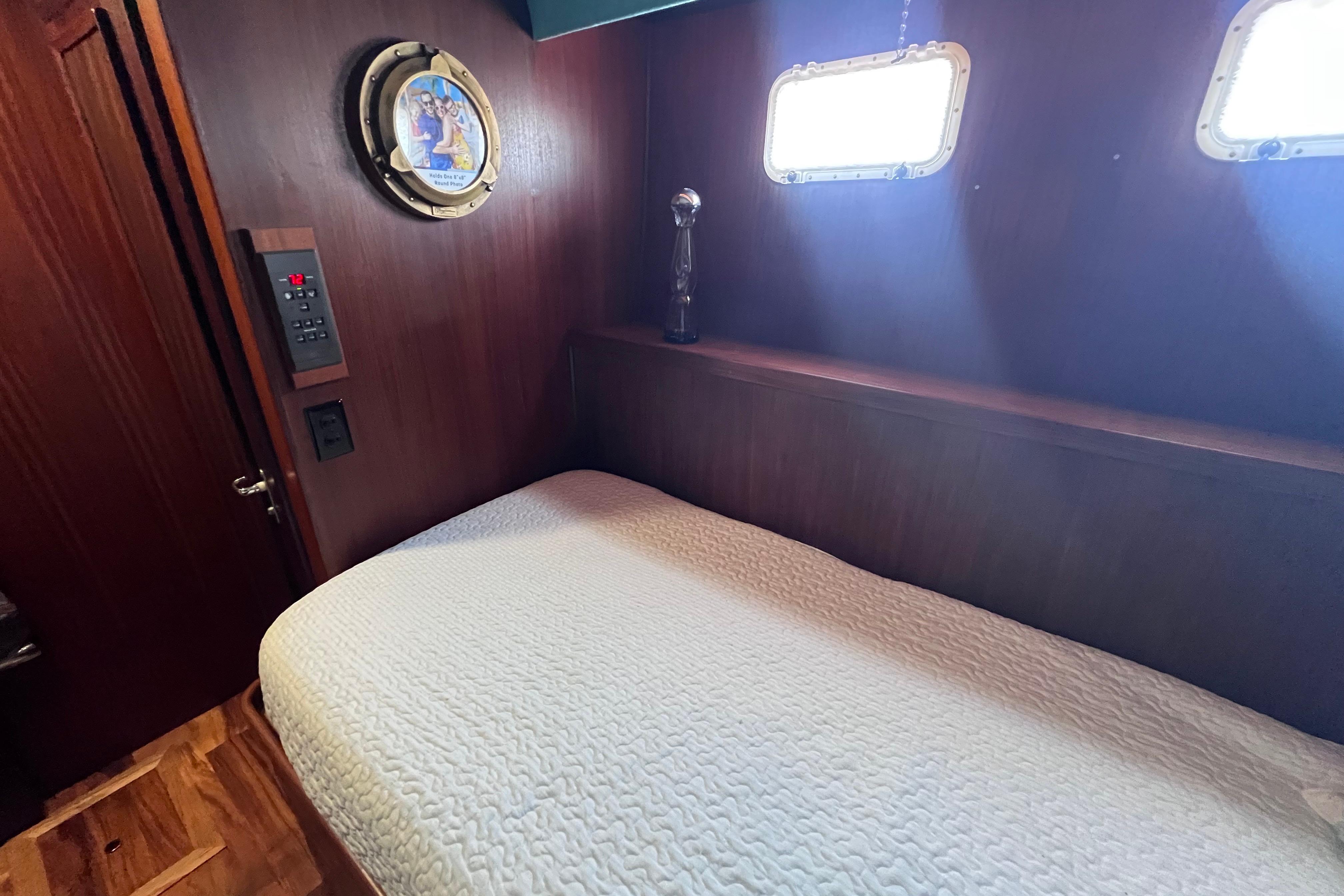Cozy cabin interior of 1987 Hatteras 70 Cockpit Motor Yacht with wooden walls and porthole.