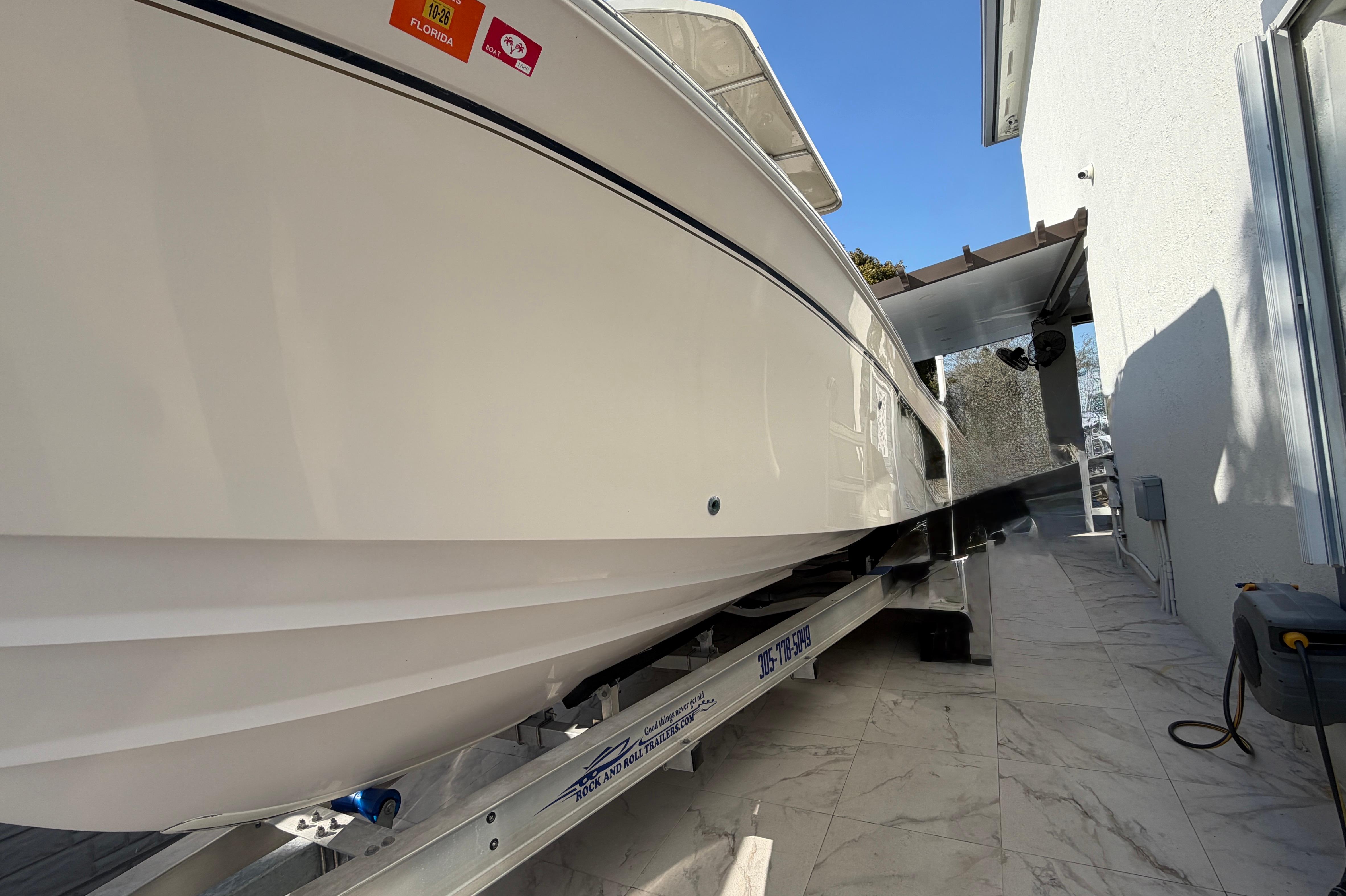 2004 Grady White 273 boat on trailer, parked beside a building under clear blue sky.