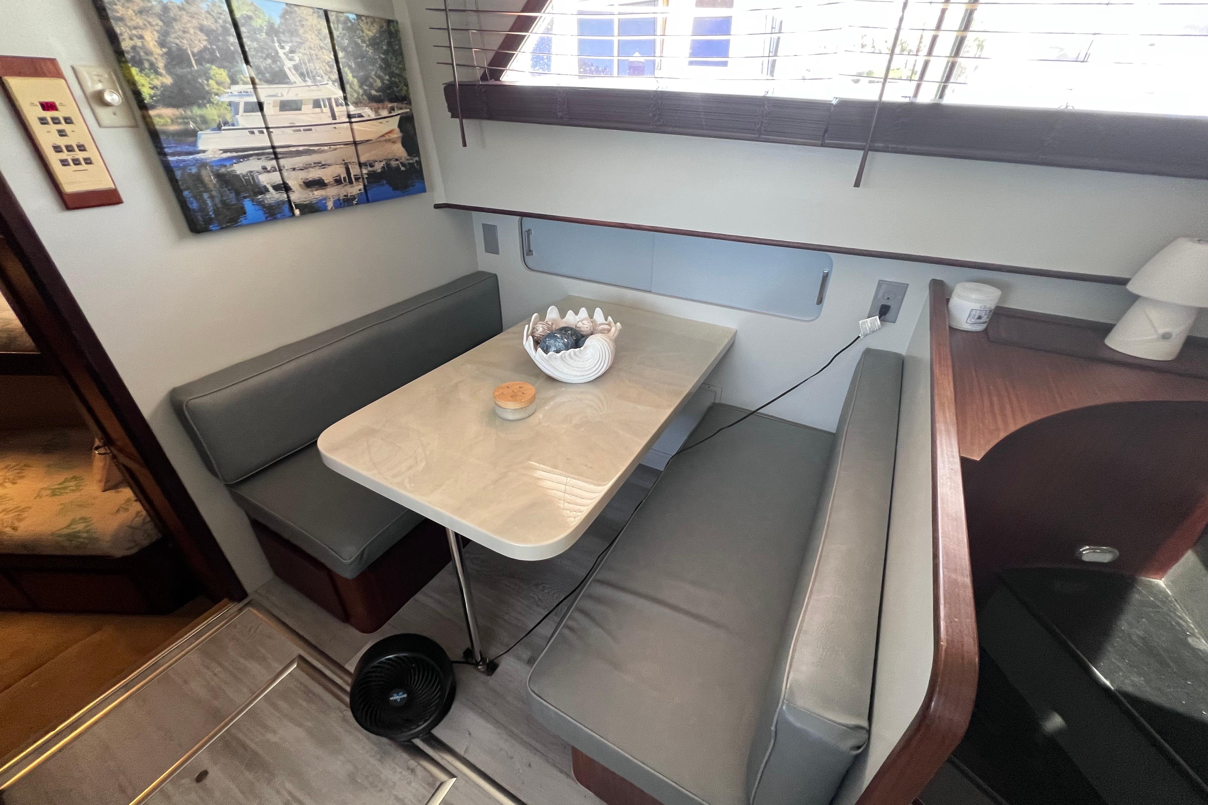 Interior of 1987 Hatteras 70 Cockpit Motor Yacht with cozy dining area and window view.