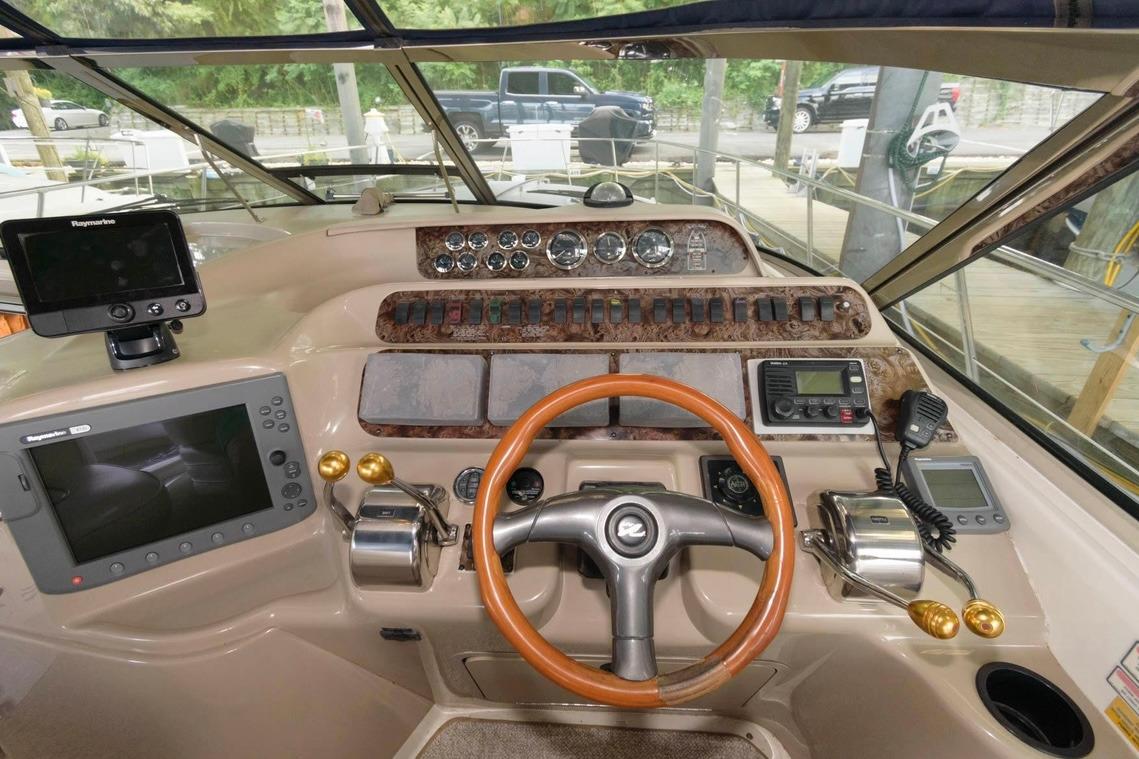1999 Sea Ray Sundancer 400 helm with navigation equipment and wooden steering wheel.