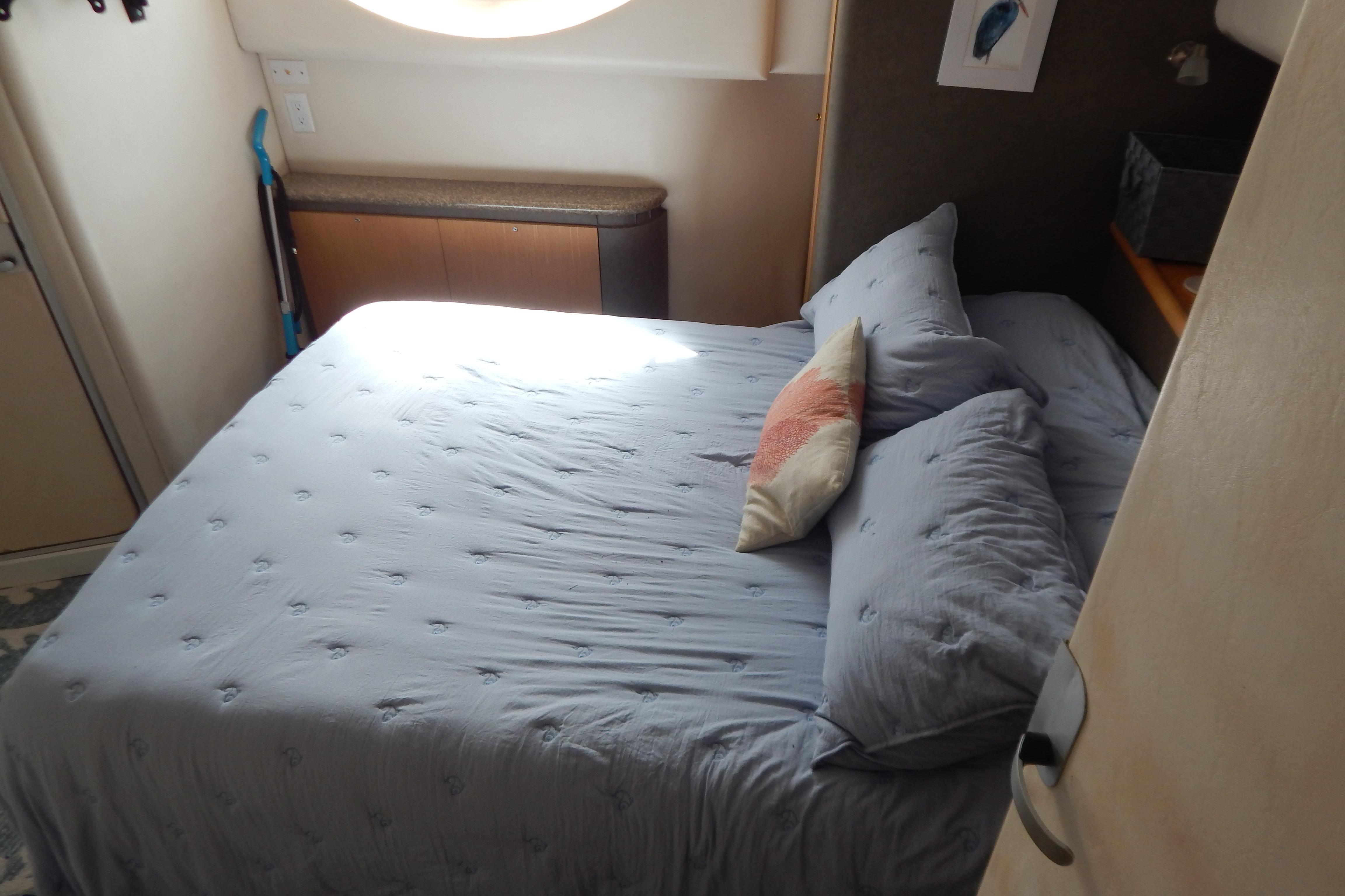Cozy bedroom in a 1998 Magnum 4100 SCR yacht with blue bedding and decorative pillows.