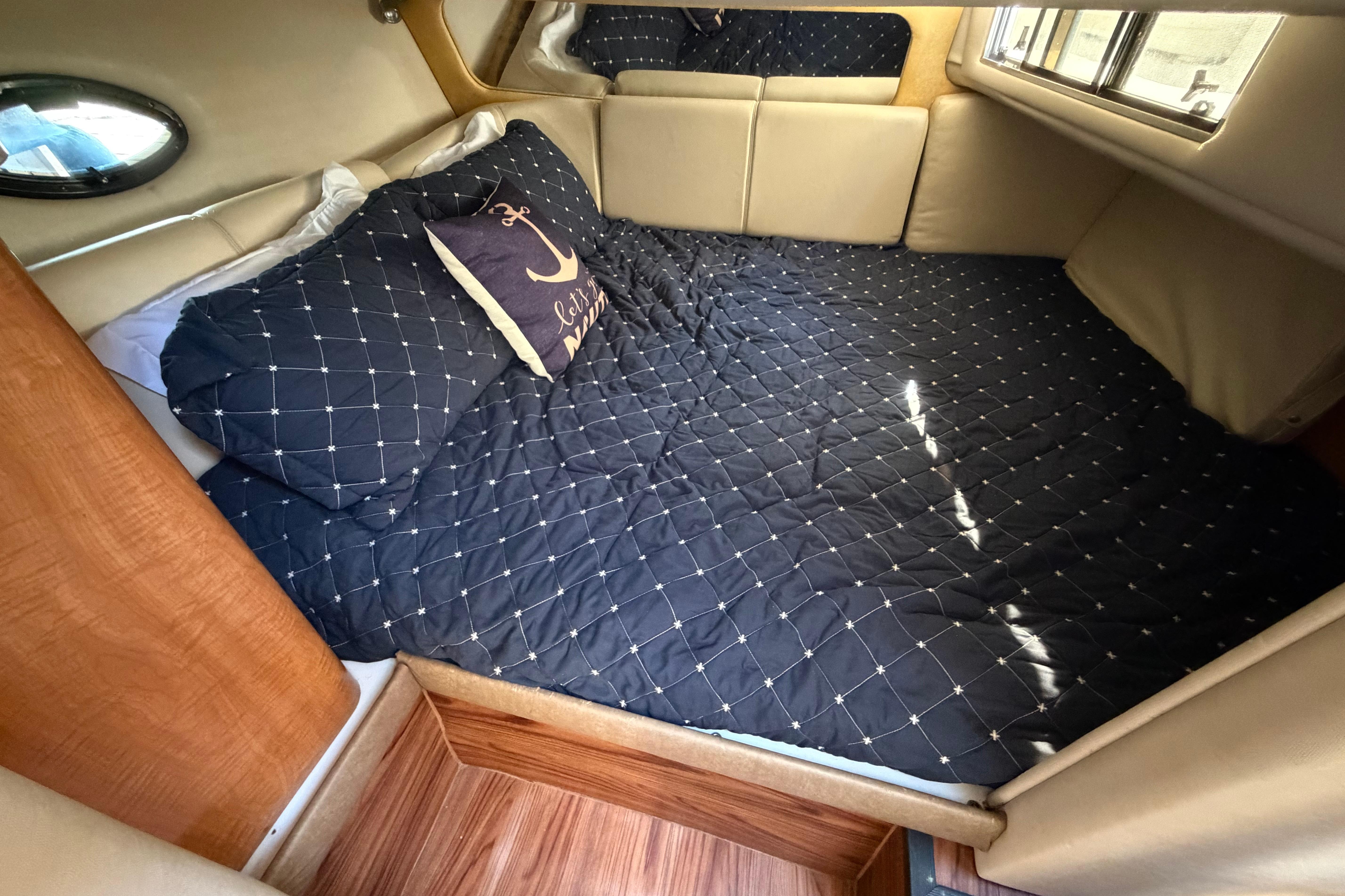 Cozy cabin interior of 2003 Regal Commodore 3260 with nautical-themed bedding.