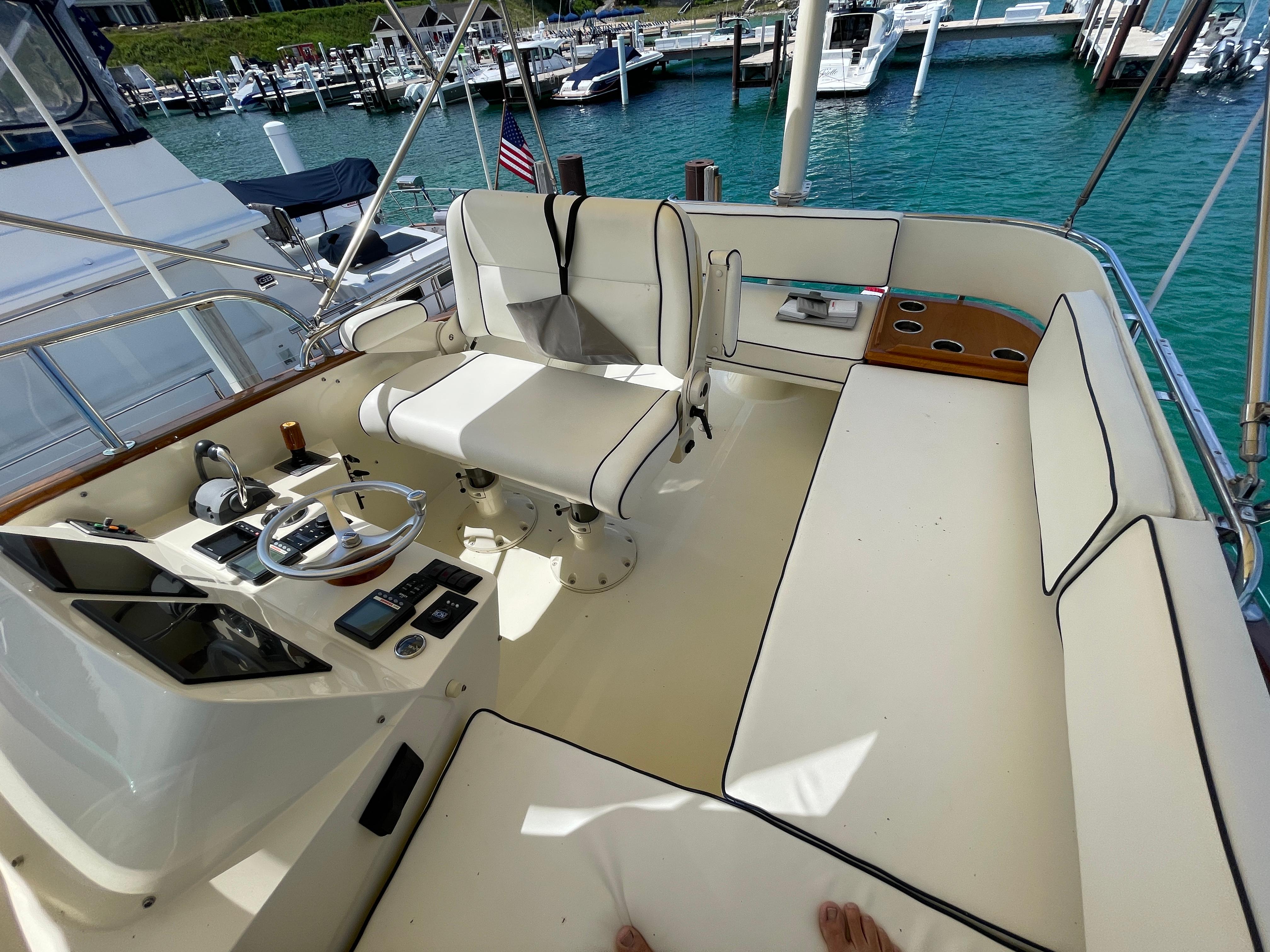 Flybridge of 2007 Hinckley Talaria 44 with white seating and control panel, docked at marina.