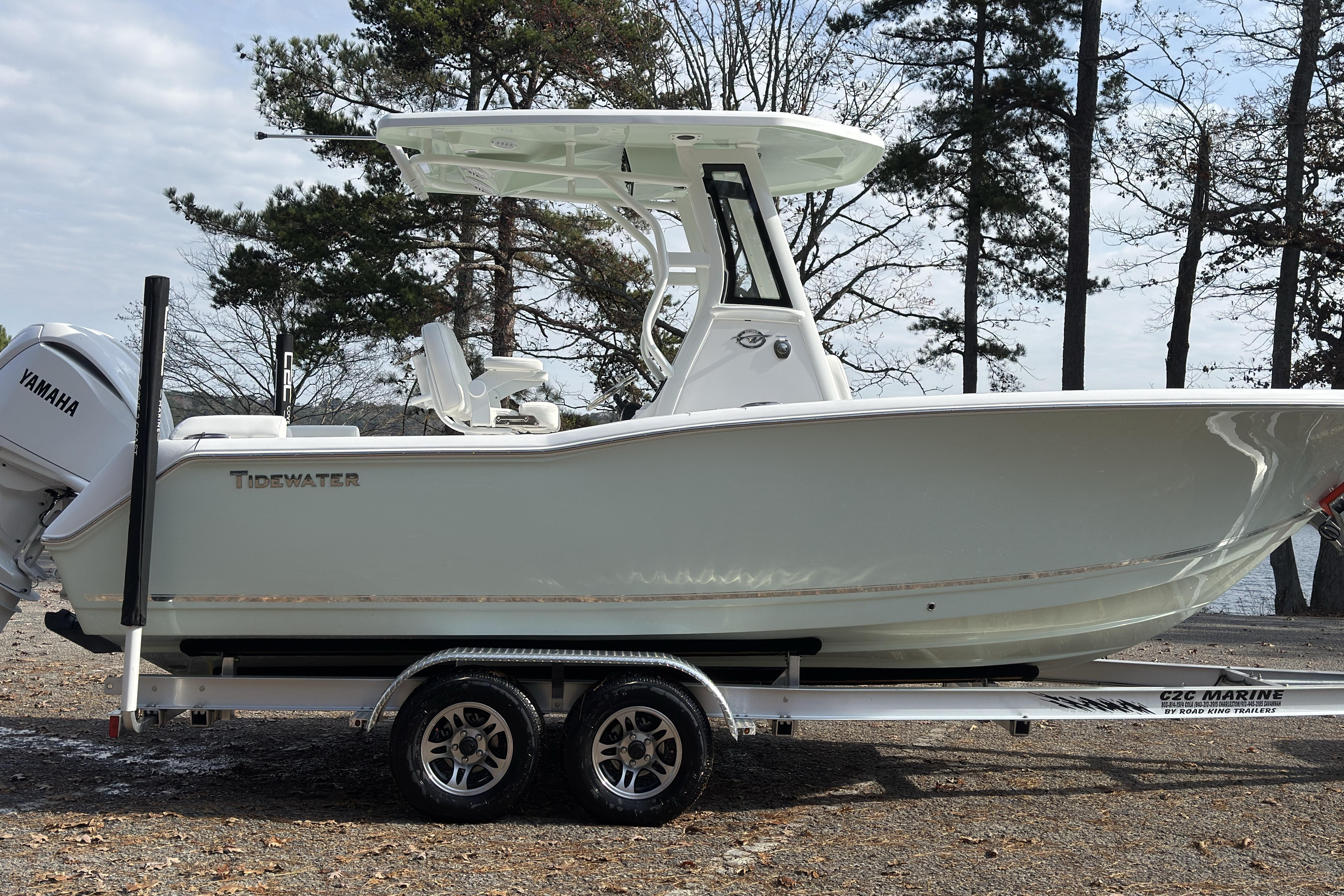 2026 Tidewater 232 LXF boat on trailer, parked near trees and water.