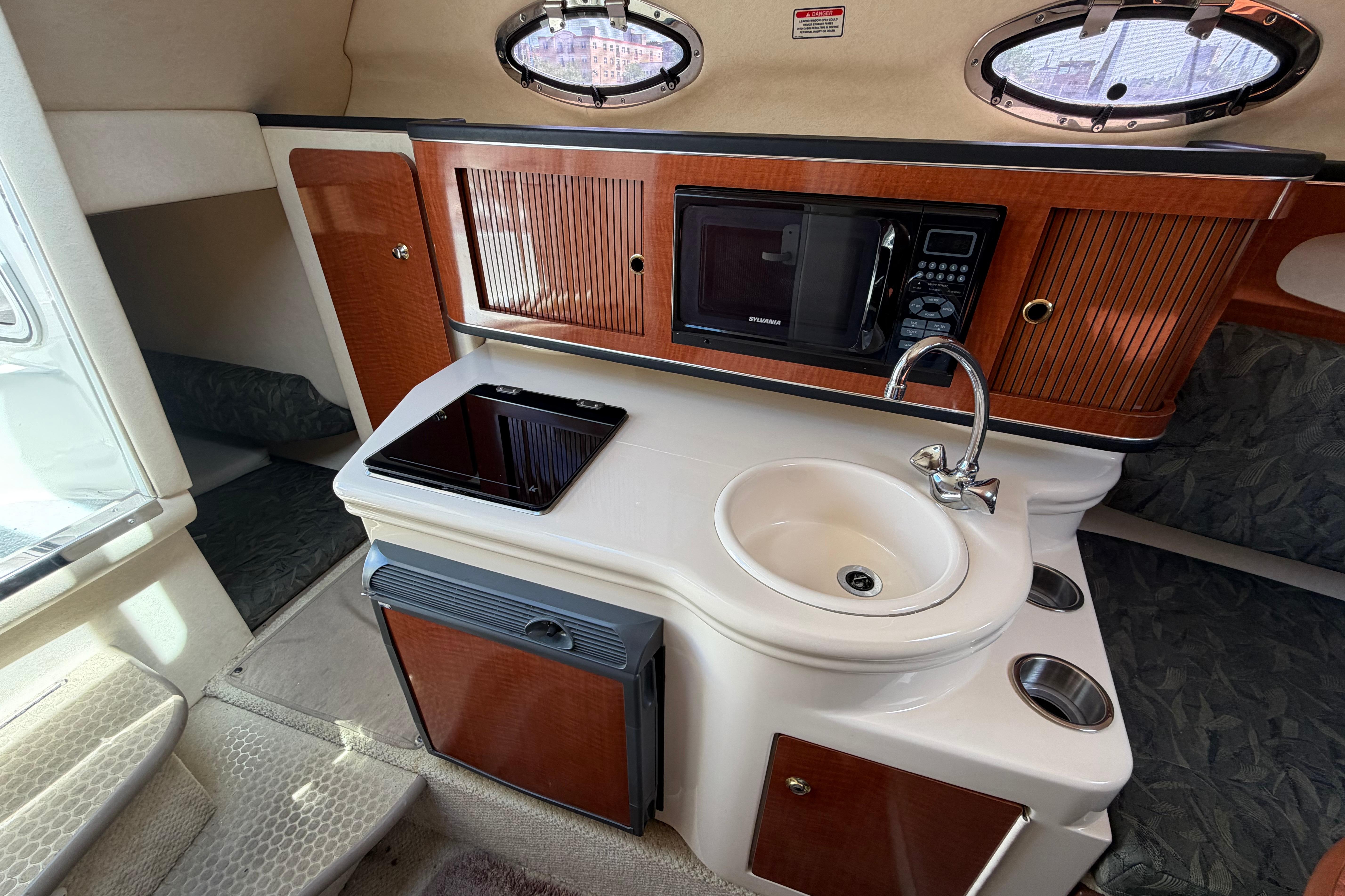 2004 Sea Ray Sundancer 260 cabin interior with kitchenette, sink, and microwave.