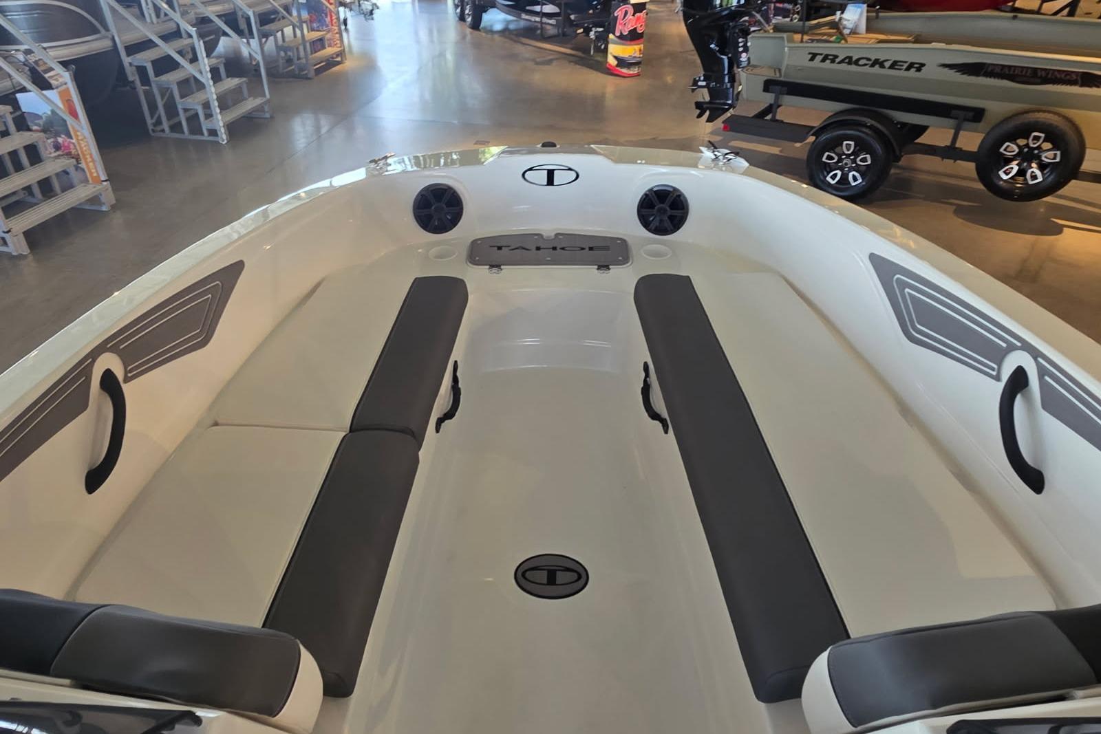 2026 Tahoe T21 boat interior with seating and storage, displayed in a showroom.